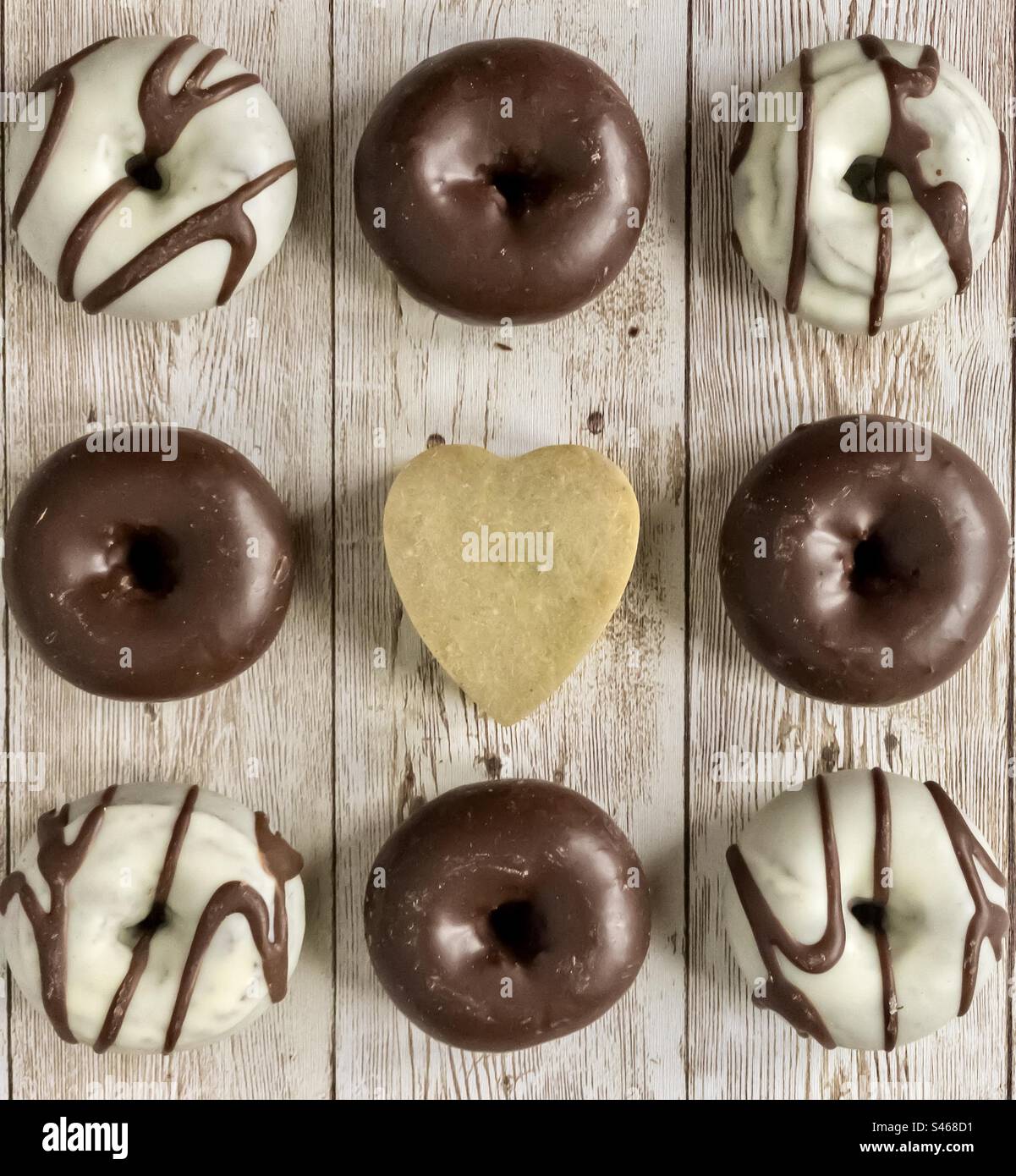 Ciambelle bianche e cioccolato fondente su fondo di legno Foto Stock