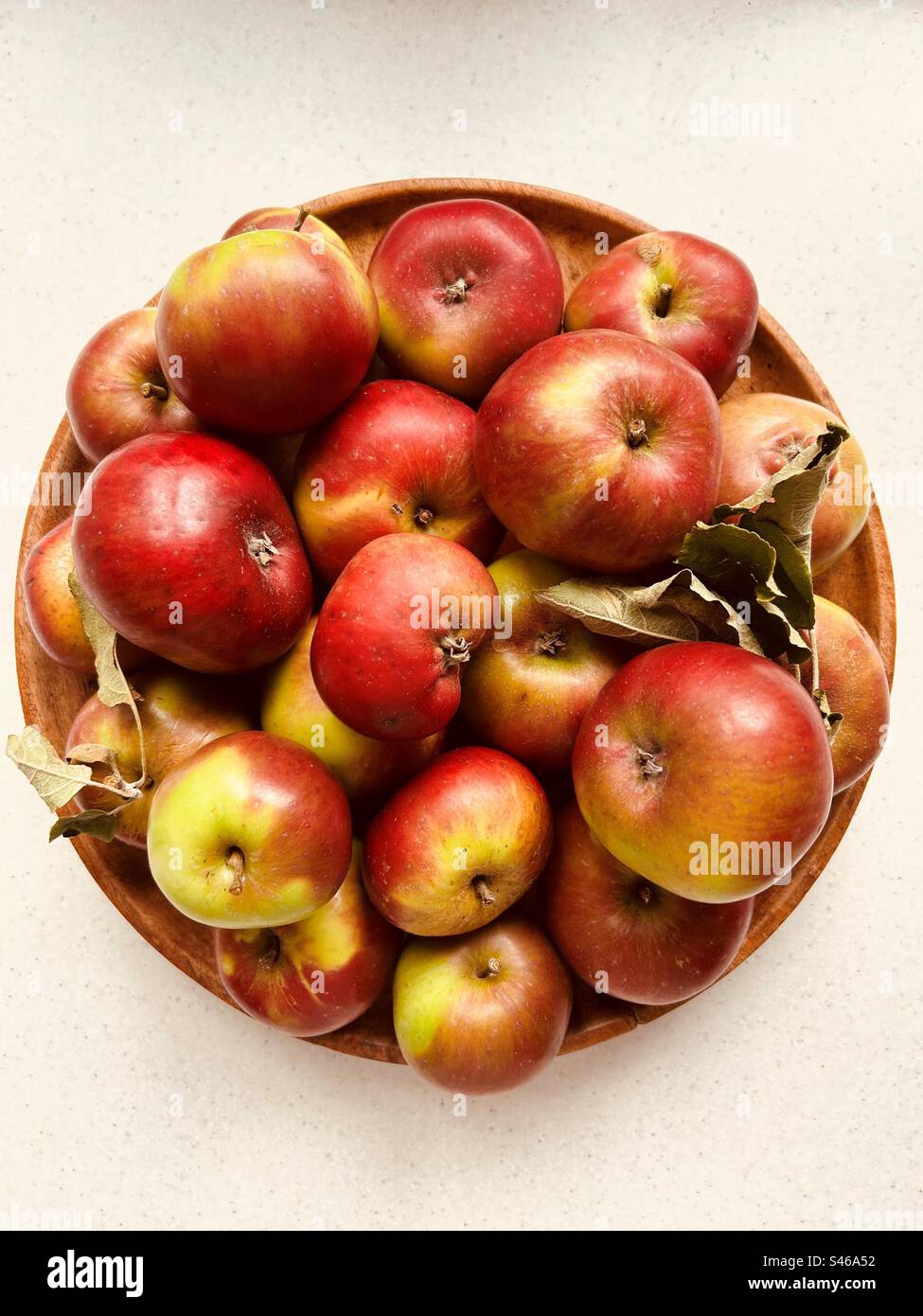 Mele colmate in un piatto circolare di legno. Mele rosse e verdi. E' stato raccolto ieri nel frutteto della comunità locale. Fresco e succoso. Foto Stock