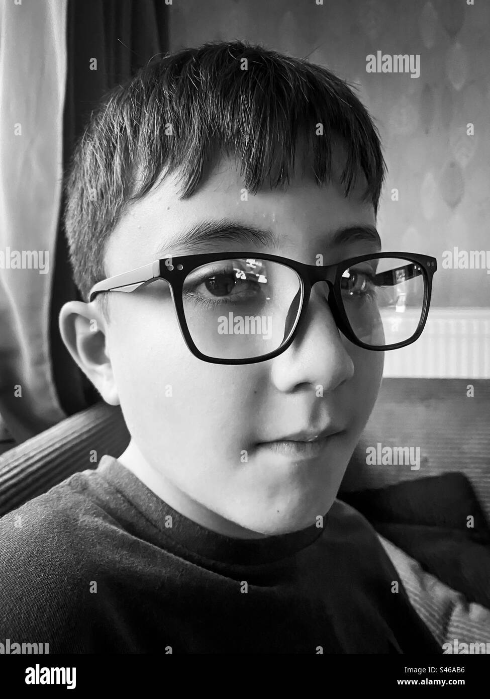 Un ritratto di un bambino di dieci anni che indossa occhiali in bianco e nero. Foto Stock