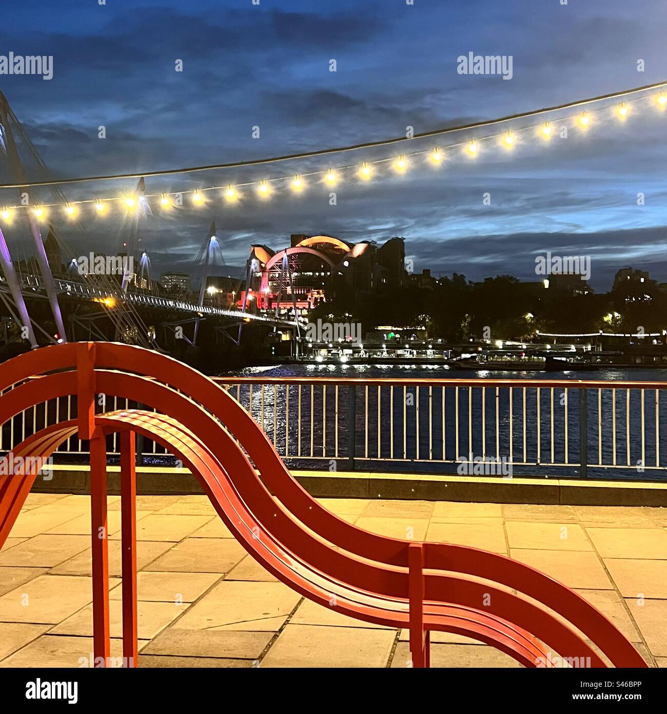 South Bank di Londra di notte con posti a sedere curvi e vista sul Tamigi Foto Stock