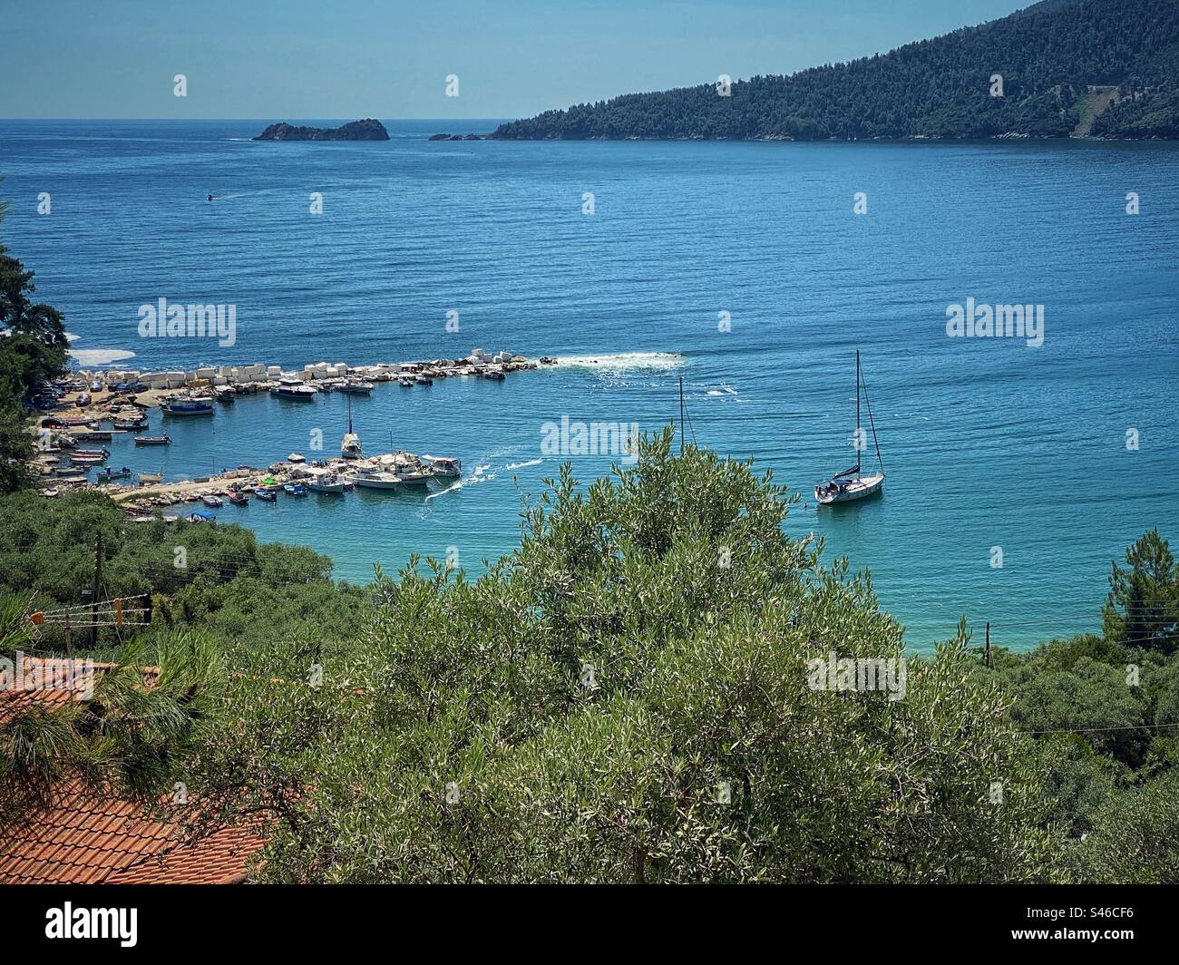 Molo con blocchi di marmo e piccole barche in una baia dietro Golden Beach sull'isola di Thassos, Grecia. - Immagine stock catturata con smartphone