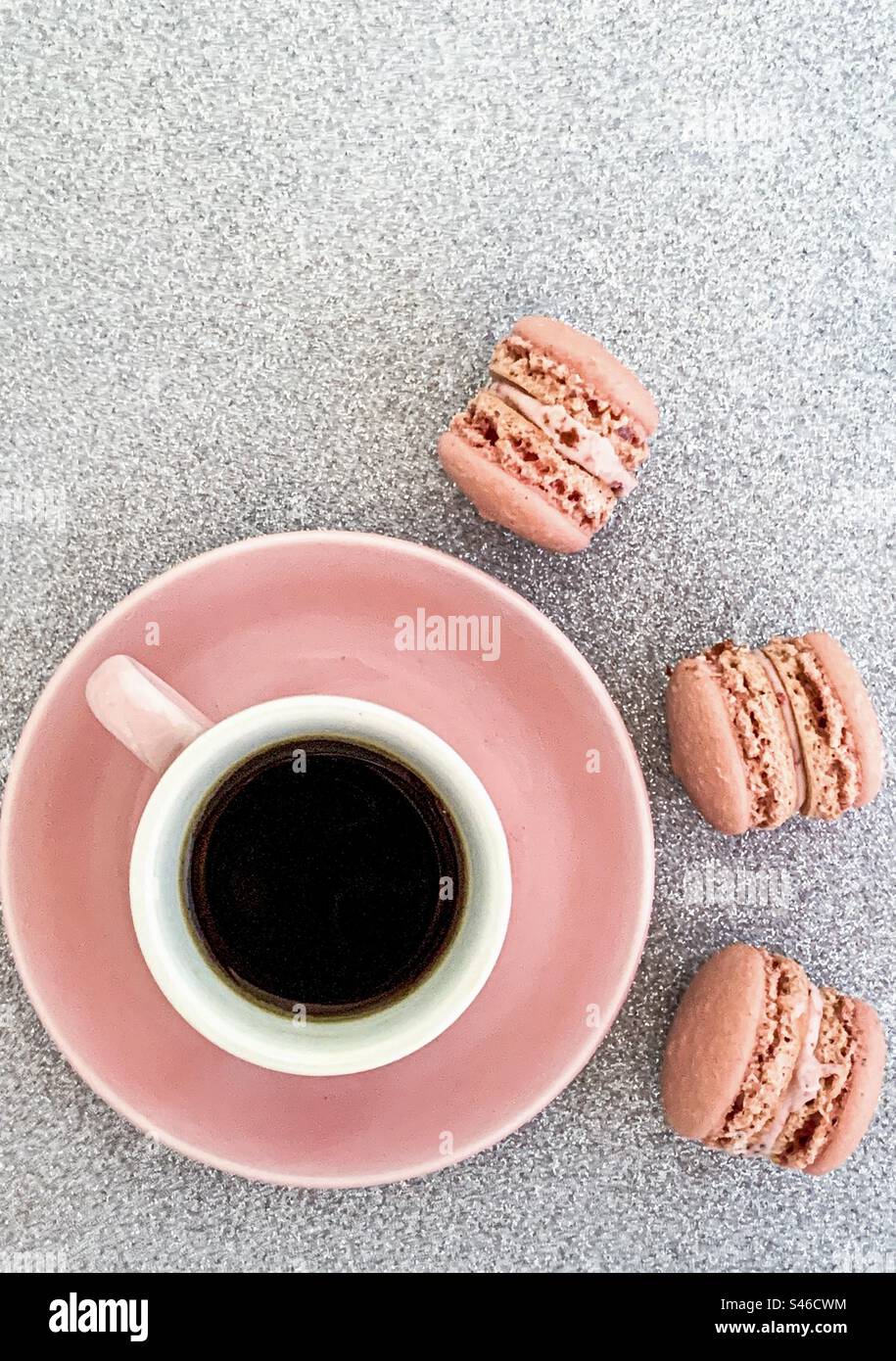 Tazza di caffè rosa con macaron rosa su sfondo glitterato argento Foto Stock