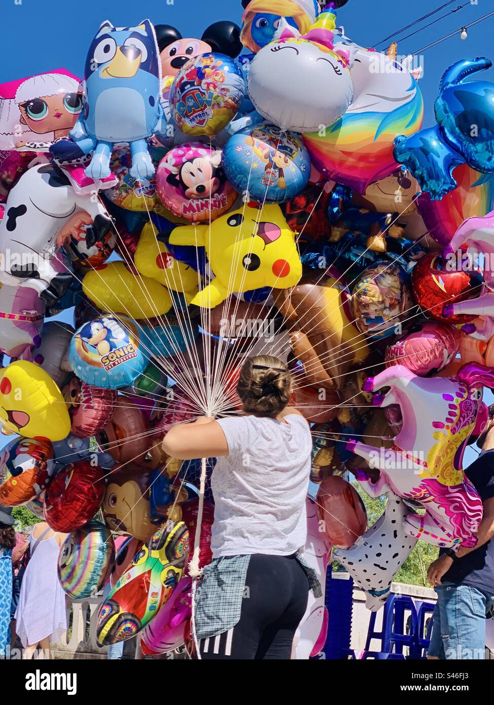 Una persona con un enorme mucchio di elio, palloncini personaggio - Immagine stock catturata con smartphone