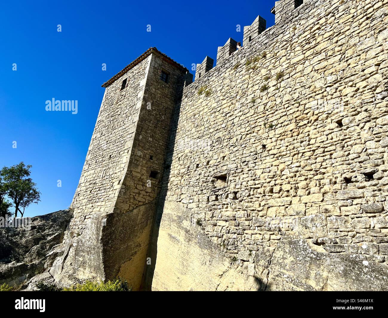 A small tower and walls of the Guaita fortress, first tower, in San Marino against a clear blue sky Foto Stock