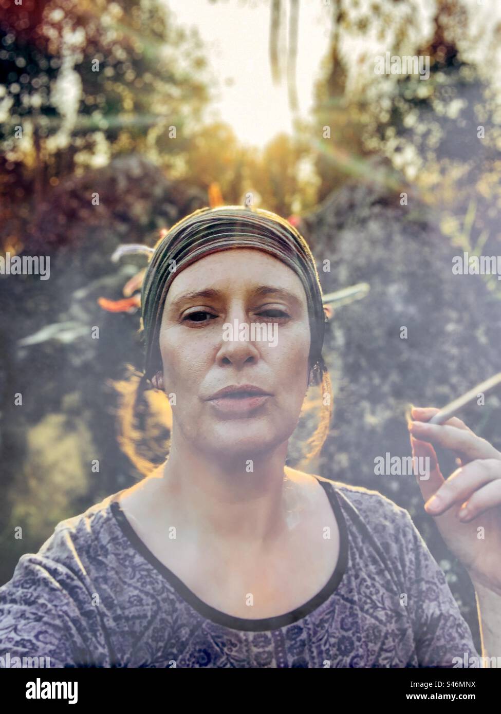 Donna che fuma un grosso spinello al tramonto Foto Stock