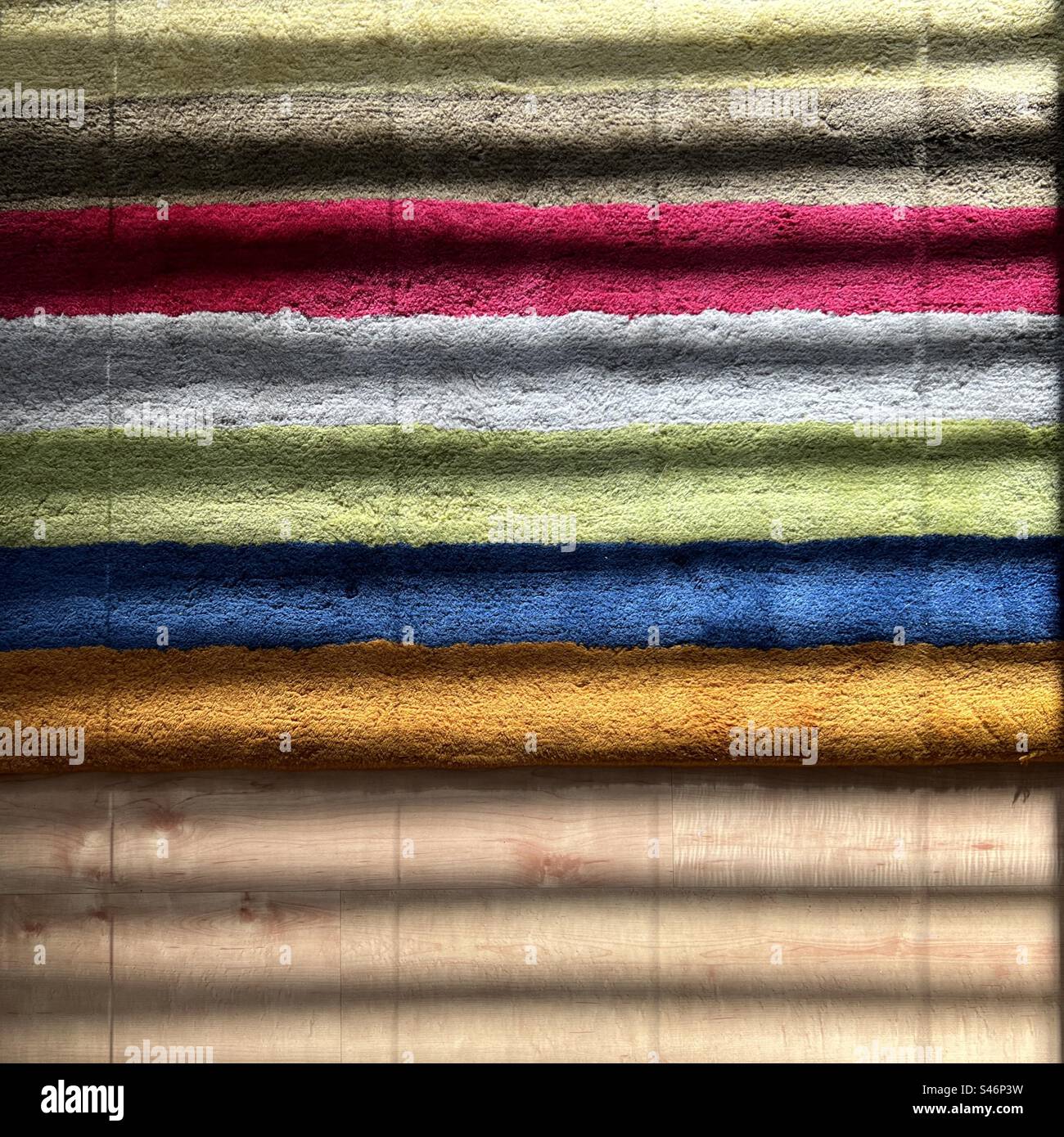 Strisce colorate su un tappeto con la luce del sole che passa attraverso le tende delle finestre, creando un motivo aggiuntivo; due strati di strisce astratte per un utile sfondo grafico Foto Stock