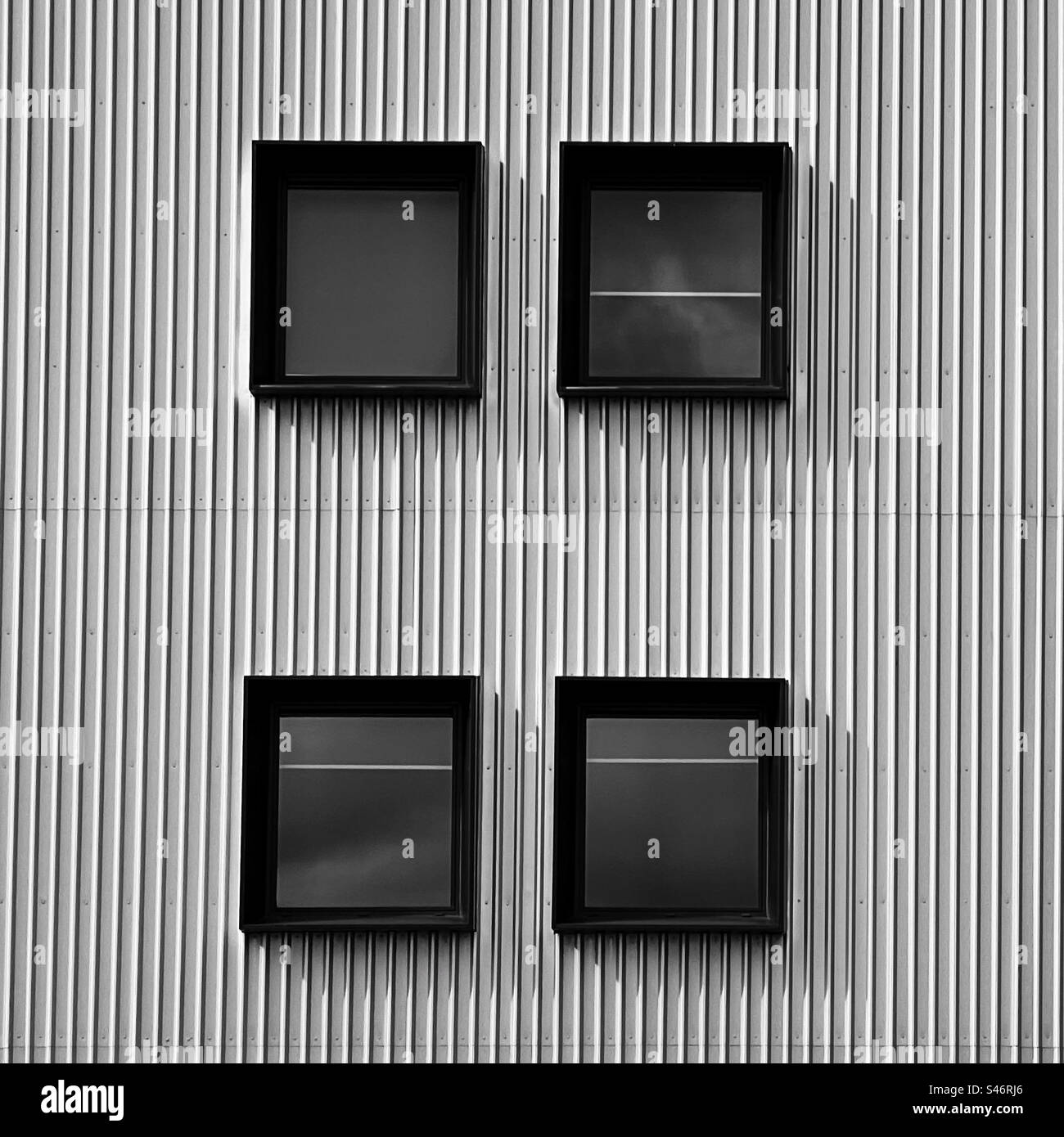 Astratte finestre quadrate collocate in una parete di metallo ondulato su un edificio moderno Foto Stock