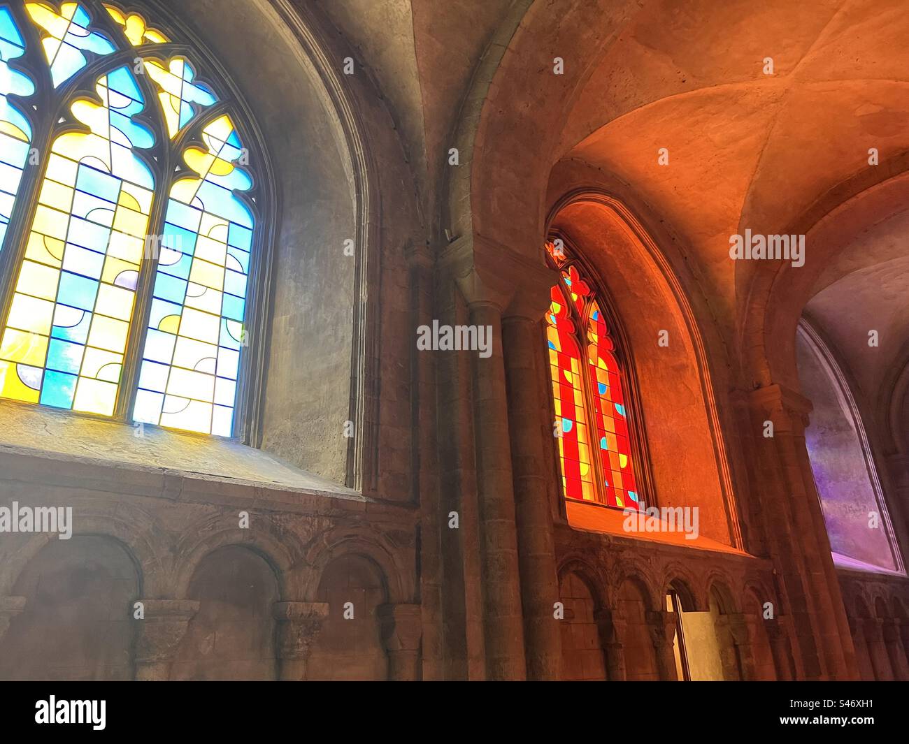 Vetrate color rosso e viola riflettenti nella cattedrale di Norwich Foto Stock