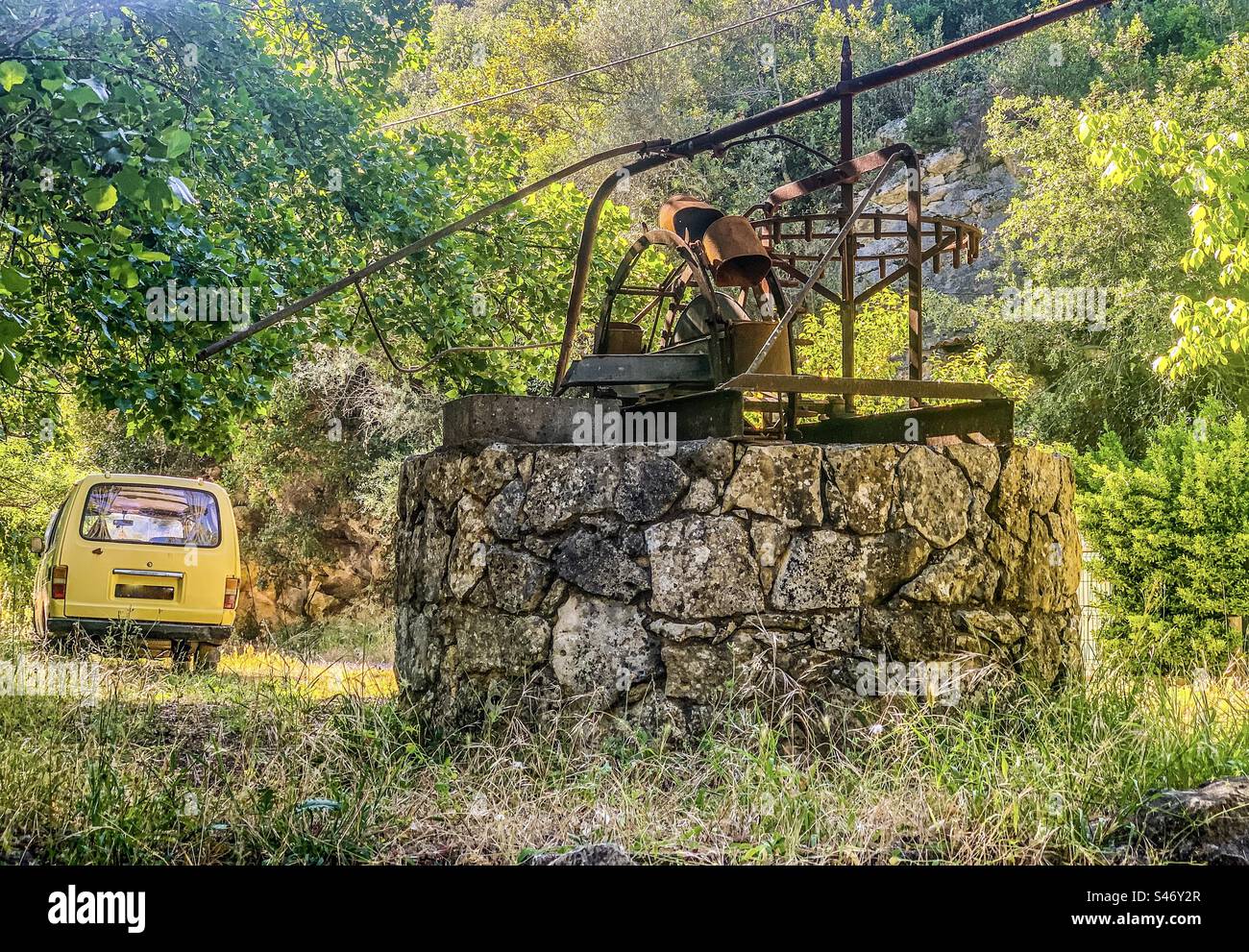 Un vecchio pozzo con camper giallo parcheggiato nelle vicinanze Foto Stock