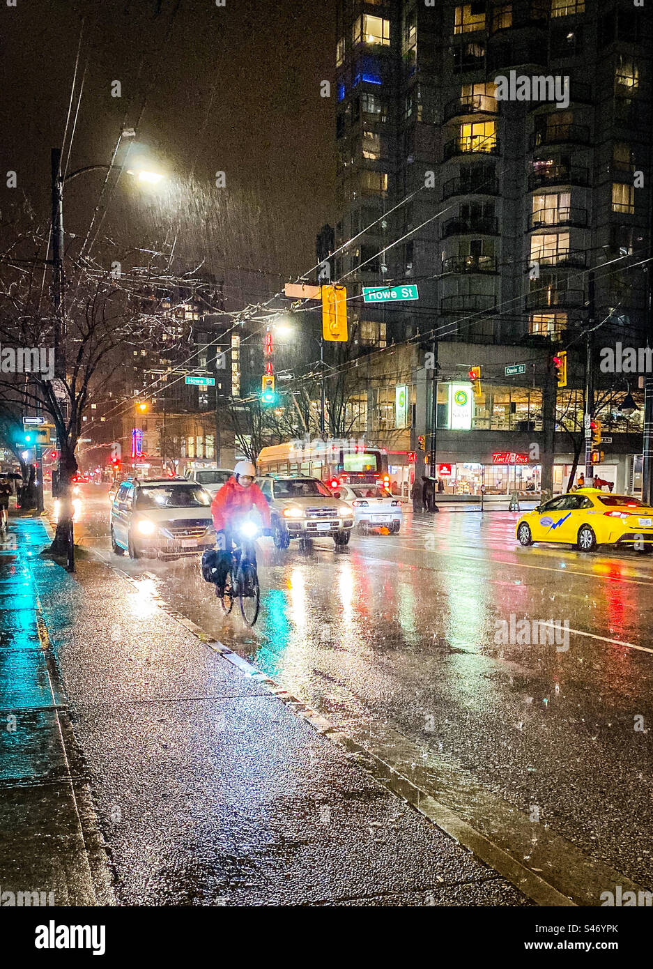 Il ciclista si appoggia alla pioggia battente per le strade di Vancouver di notte. Foto Stock