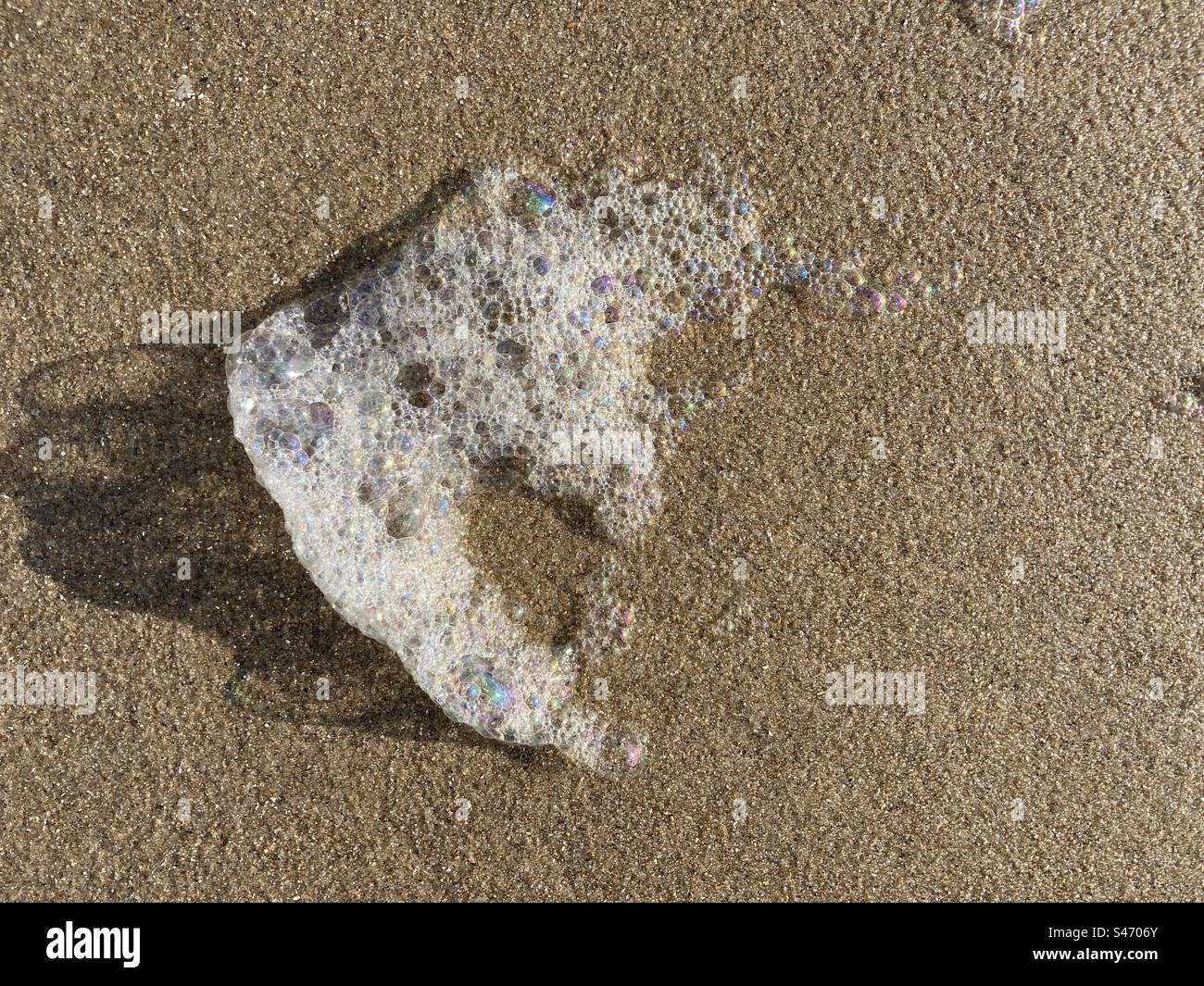 Personaggio in schiuma bianca soffiato sulla sabbia della spiaggia - Immagine stock catturata con smartphone