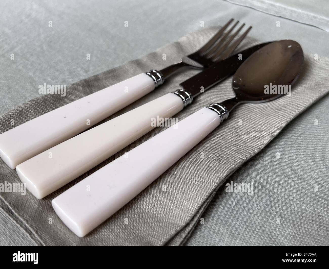 Posate bianche (coltello, forchetta e cucchiaio) su tovaglioli verdi con tovaglia verde - Immagine stock catturata con smartphone