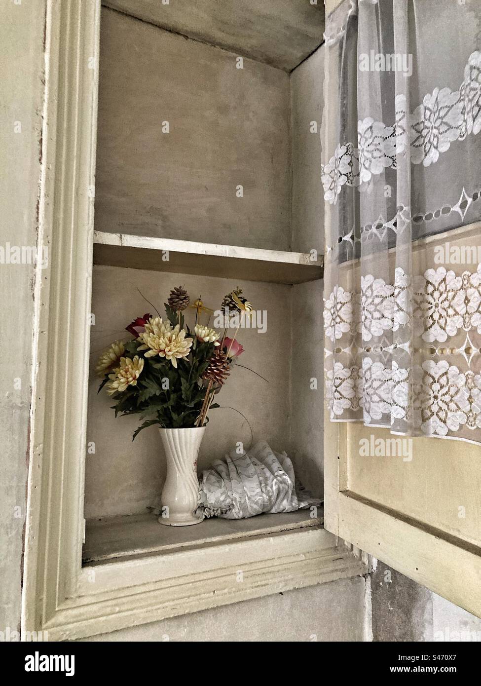 Vaso con vecchi fiori di plastica in casa vecchia e tende nell'armadietto di stoccaggio Foto Stock