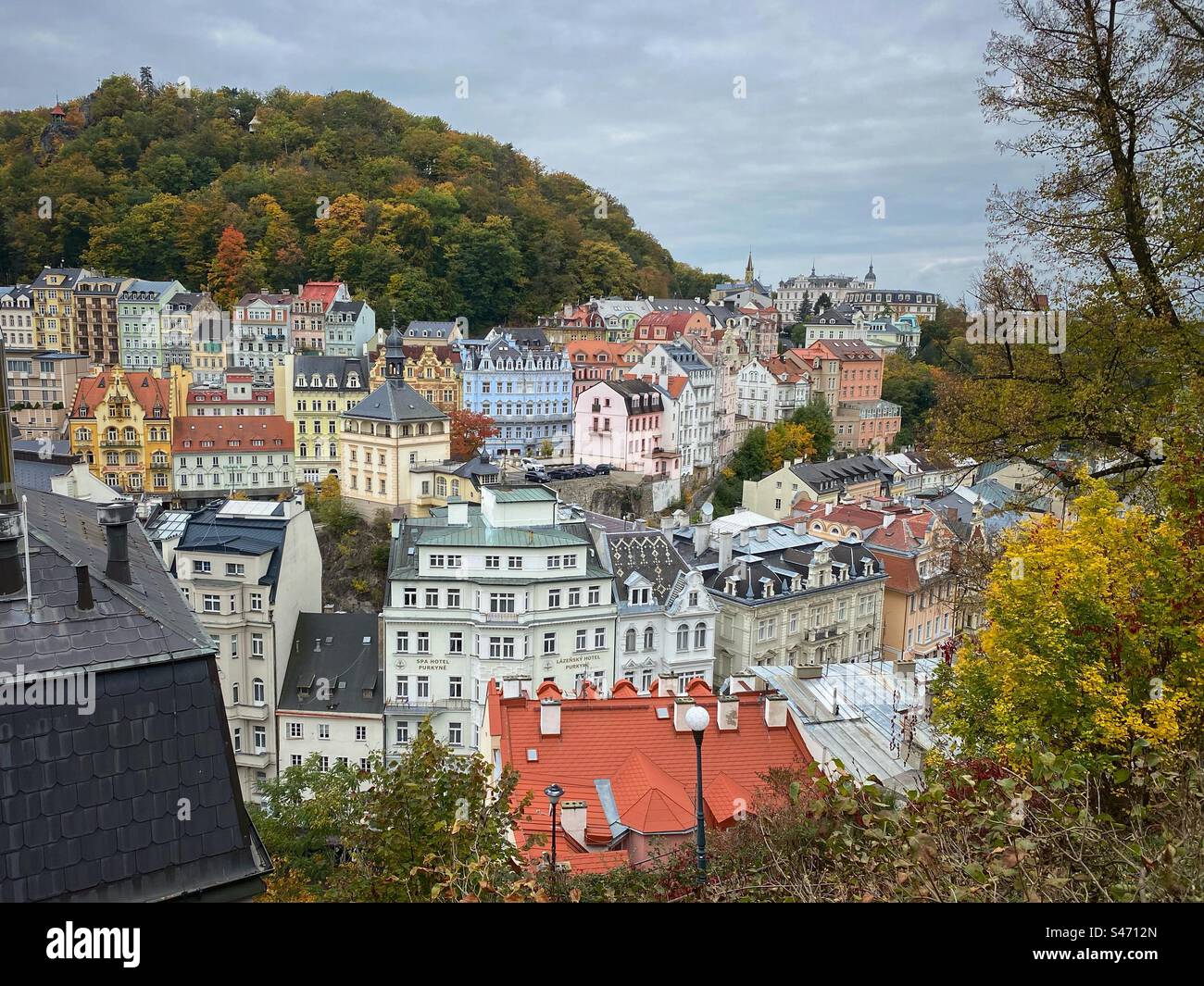 Edifici storici e colorati circondati da foreste autunnali e colline a Karlovy Vary, Repubblica Ceca. Foto Stock