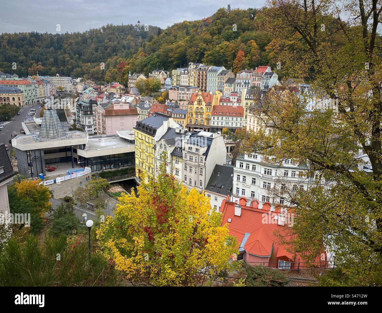 Edifici storici e colorati e colonnato con sorgenti termali circondati da foreste autunnali e colline a Karlovy Vary, Repubblica Ceca. Foto Stock
