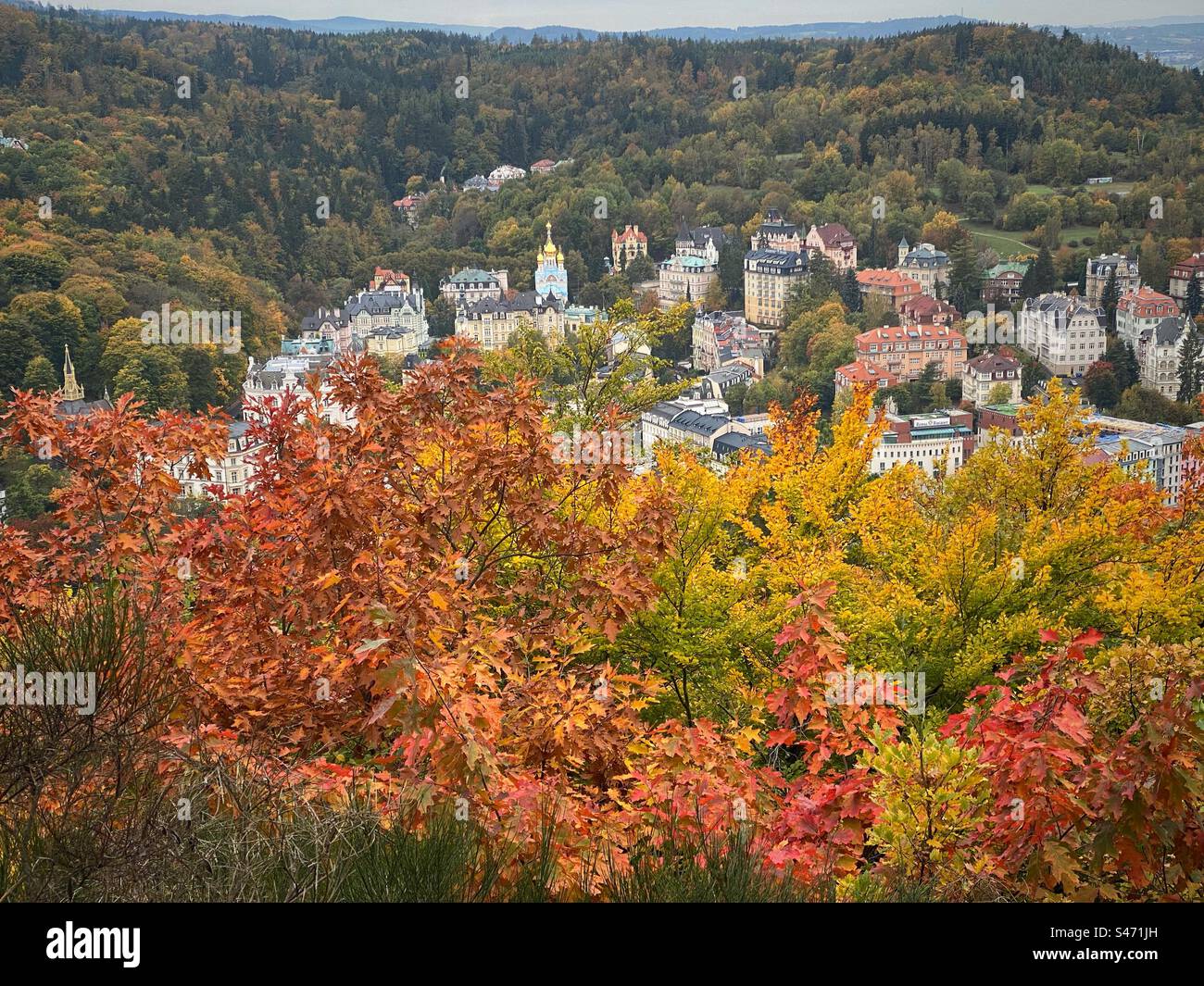 Vista panoramica dei vecchi edifici di Karlovy Vary, circondata da colline e luminosi alberi autunnali, Repubblica Ceca. - Immagine stock catturata con smartphone