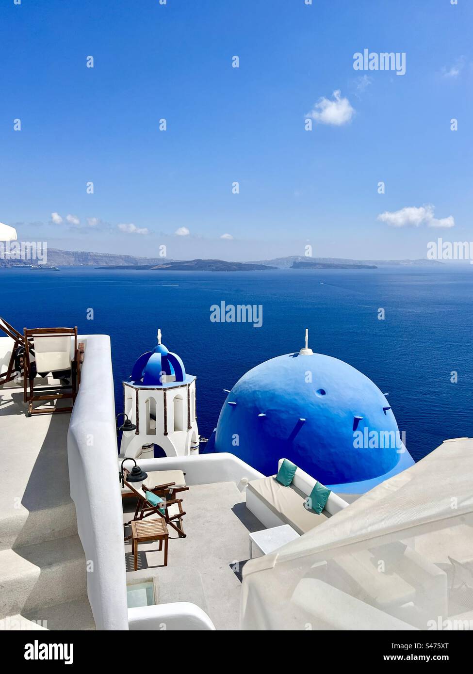 La chiesa di San Spyridon con la sua cupola blu e il campanile sotto le terrazze sul ripido pendio della costa di Oia che conduce alla caldera di Santorini. - Immagine stock catturata con smartphone