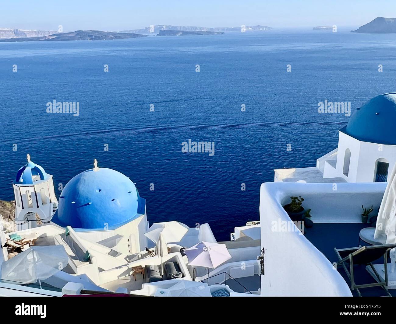 La chiesa di Anastasia e la chiesa di Spyridon con il suo campanile associato tra edifici lavati di bianco sul ripido pendio di Oia sopra la caldera di Santorini. Foto Stock