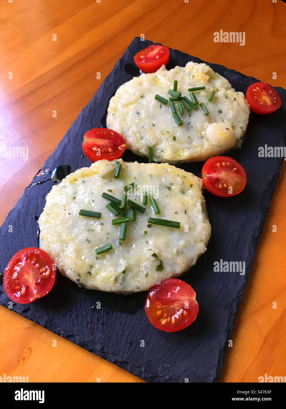 Hamburger di pesce con pomodori ciliegini. Foto Stock