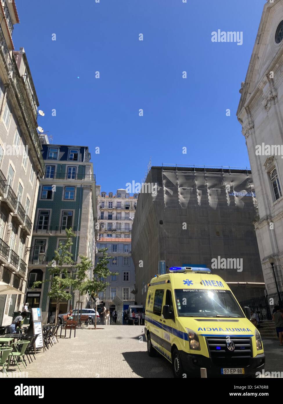 Ambulanza gialla in via Lisbona, su un'area acciottolata, con edifici tipici intorno Foto Stock