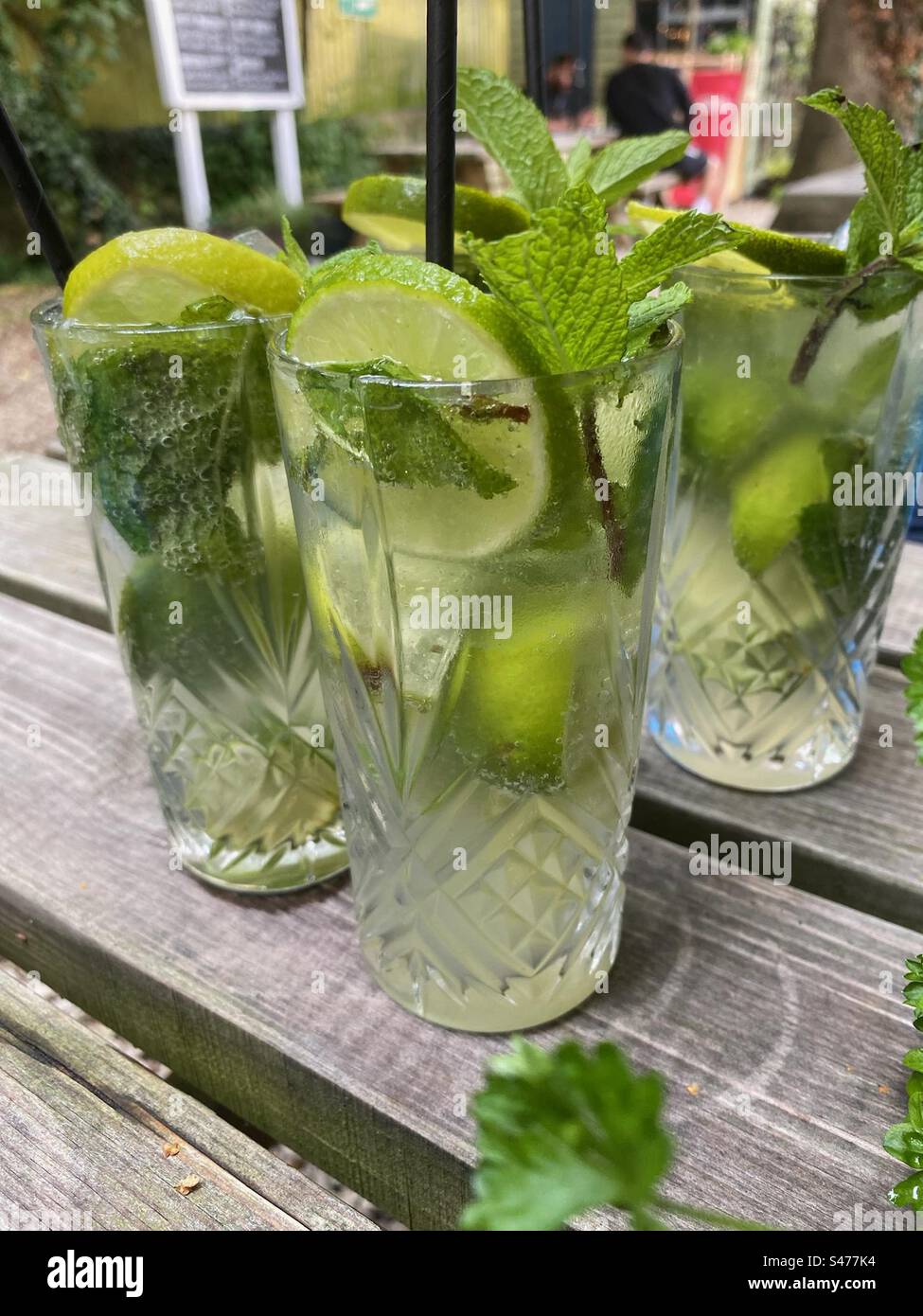 Bicchieri alti di cocktail mojito con ghiaccio, menta, lime e cannuccia Foto Stock