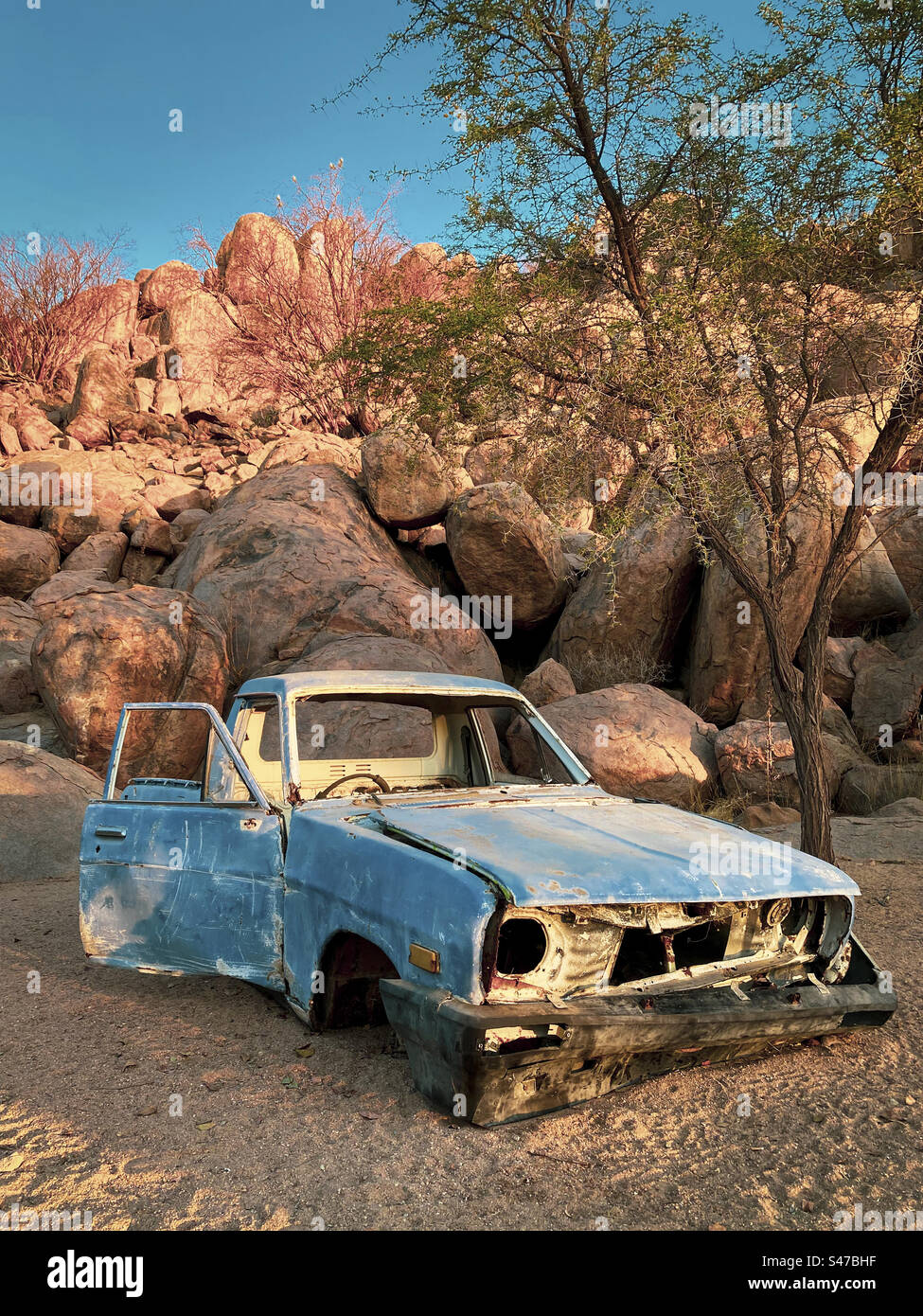 Una vecchia auto abbandonata viene lasciata decadere vicino alle rocce in un campeggio a Erongo, Namibia Foto Stock