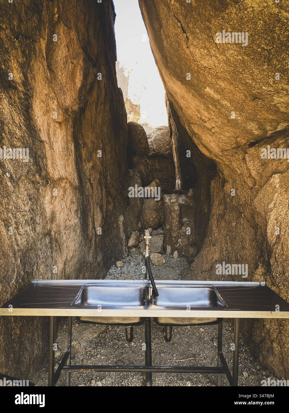 Un lavandino da cucina in acciaio inox tra grandi rocce in un campeggio in Namibia Foto Stock