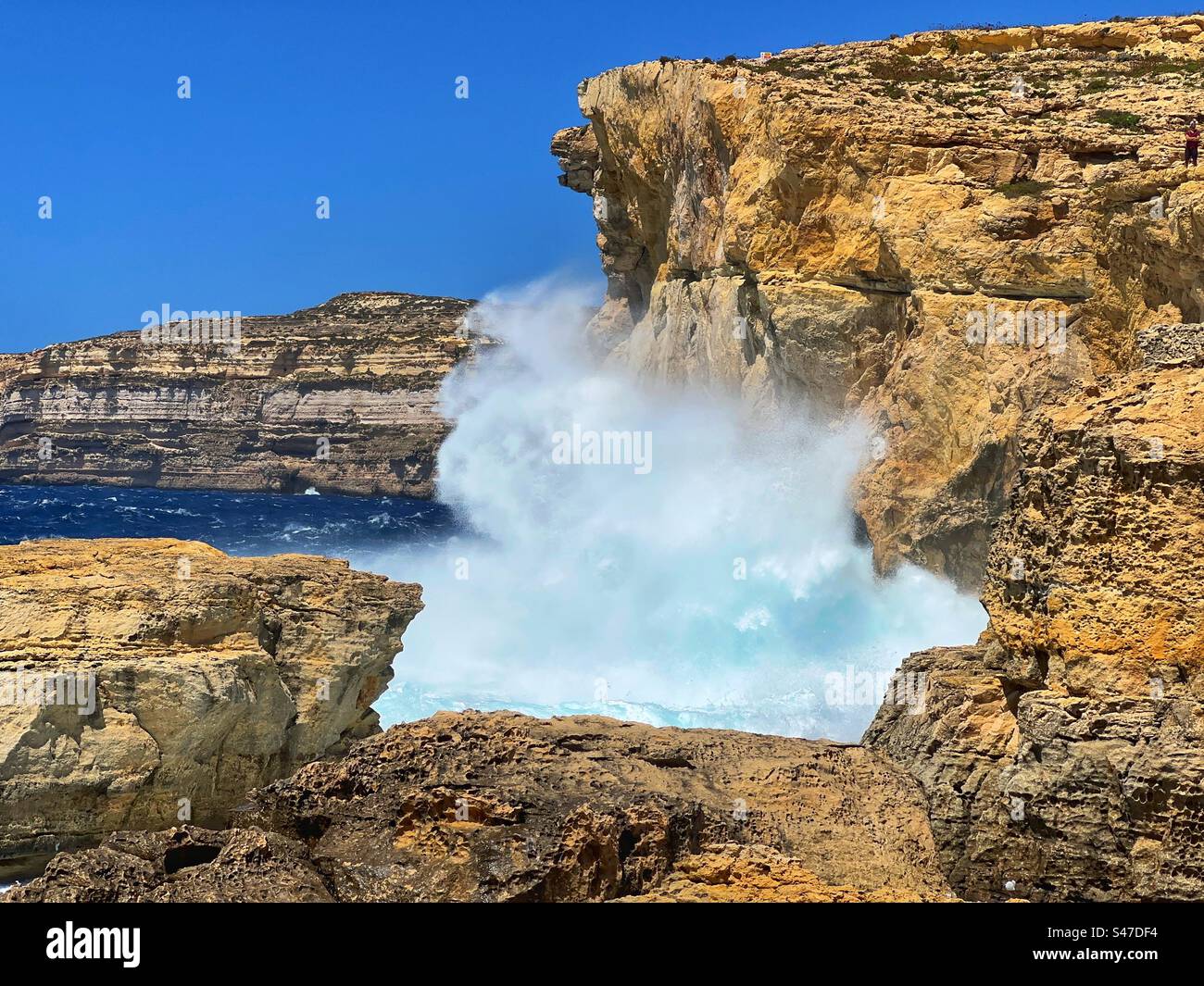 Spruzza da una grande onda che colpisce le rocce sulla costa di Gozo a Malta Foto Stock