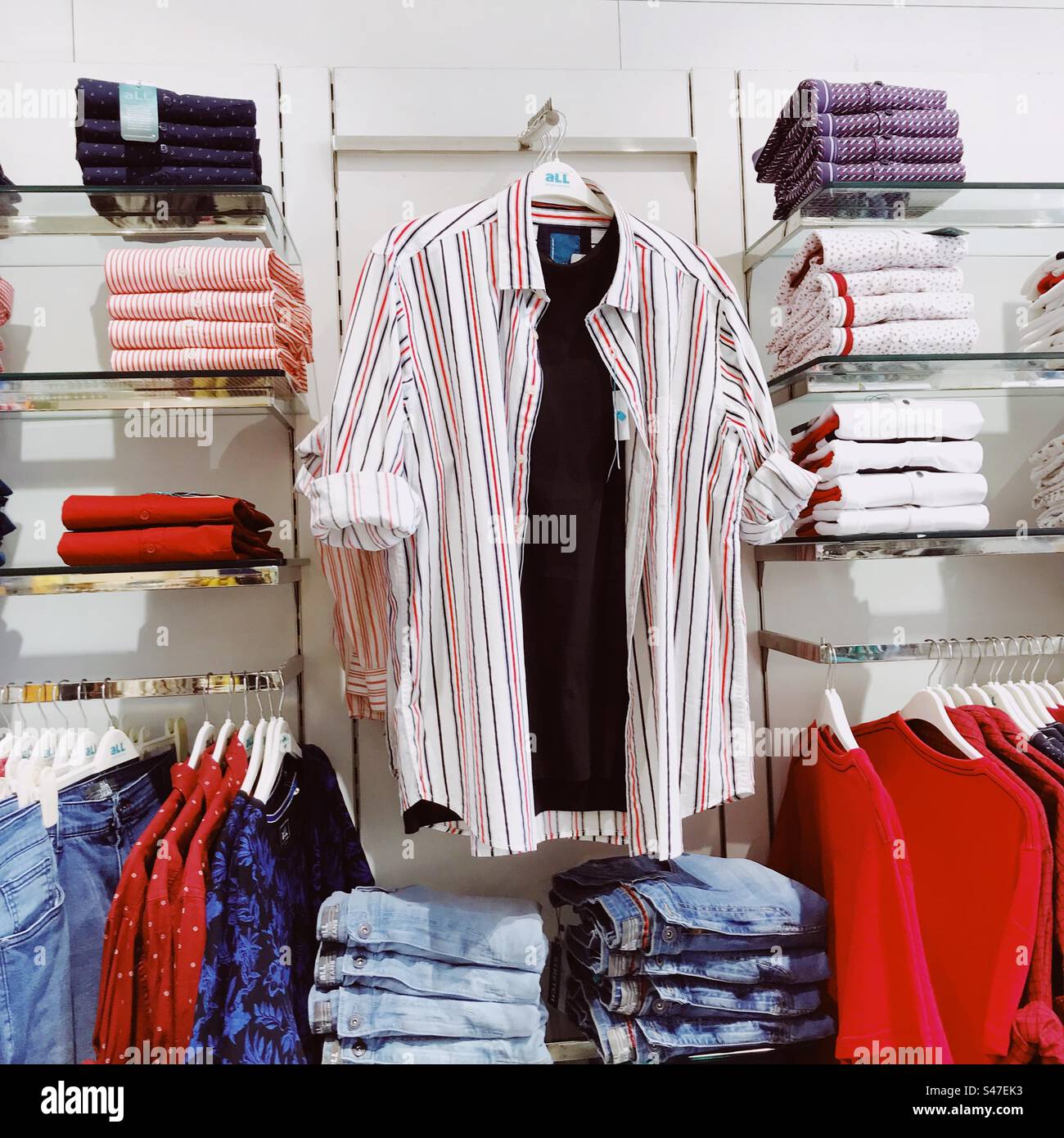 Camicie e pantaloni jeans in vendita presso il negozio di abbigliamento di un centro commerciale - Immagine stock catturata con smartphone