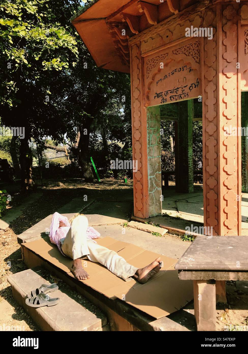 Un uomo che fa un pisolino pomeridiano davanti a un monumento storico in India Foto Stock