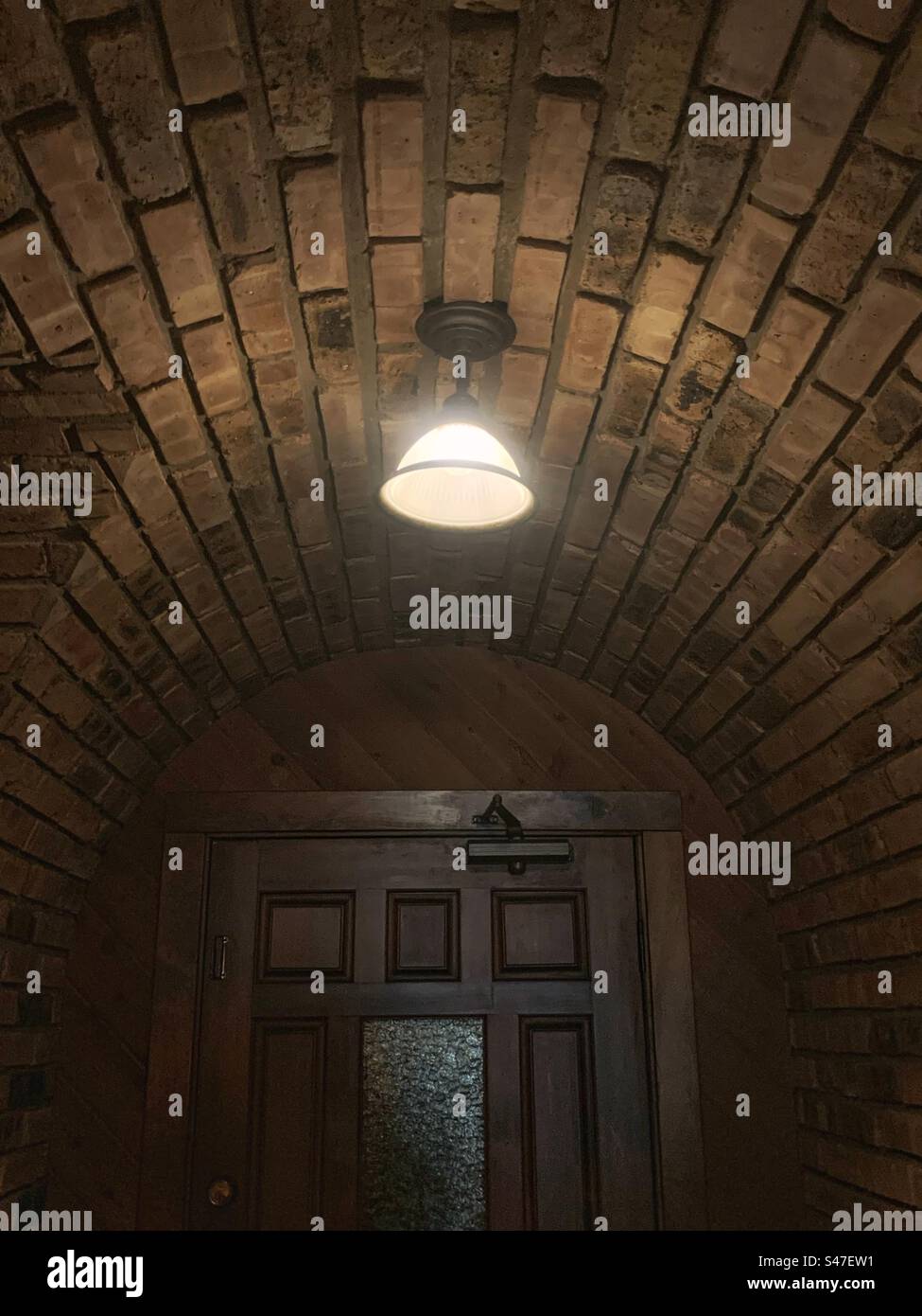 Una plafoniera luminosa che brilla in un corridoio buio. Foto Stock