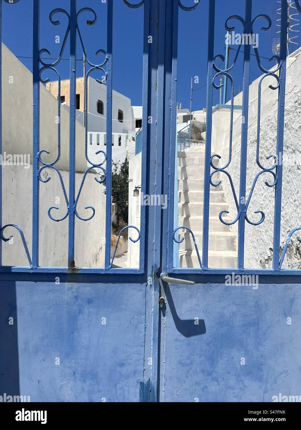 Cancello blu con edifici bianchi sullo sfondo dell'isola di Santorini. - Immagine stock catturata con smartphone