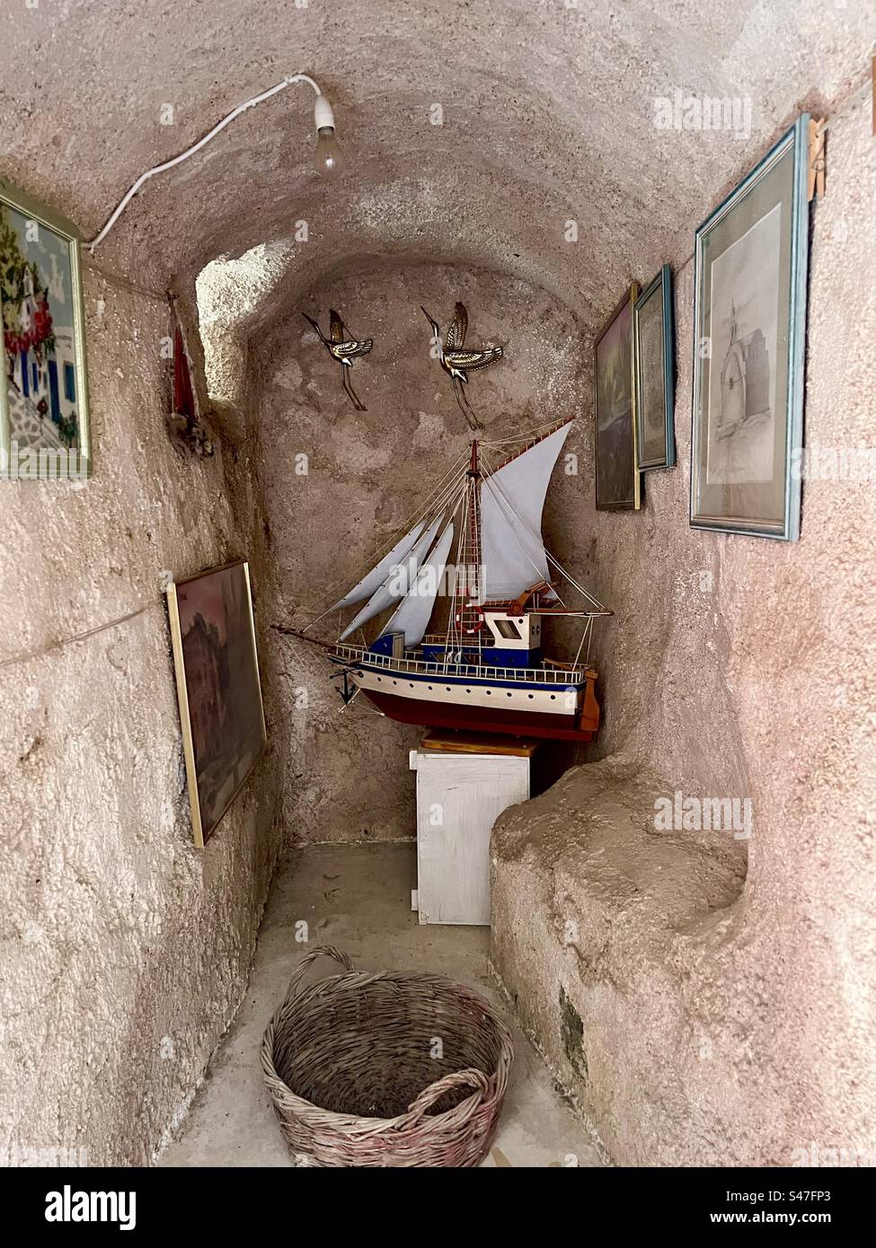 Foto appese alle pareti e altre decorazioni all'interno di un'alcova di una misteriosa grotta sotterranea a Megalochori, Santorini. - Immagine stock catturata con smartphone