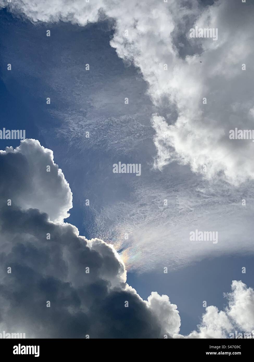 Luce arcobaleno che sbircia dietro un contorno vivido di nuvole nel cielo Foto Stock