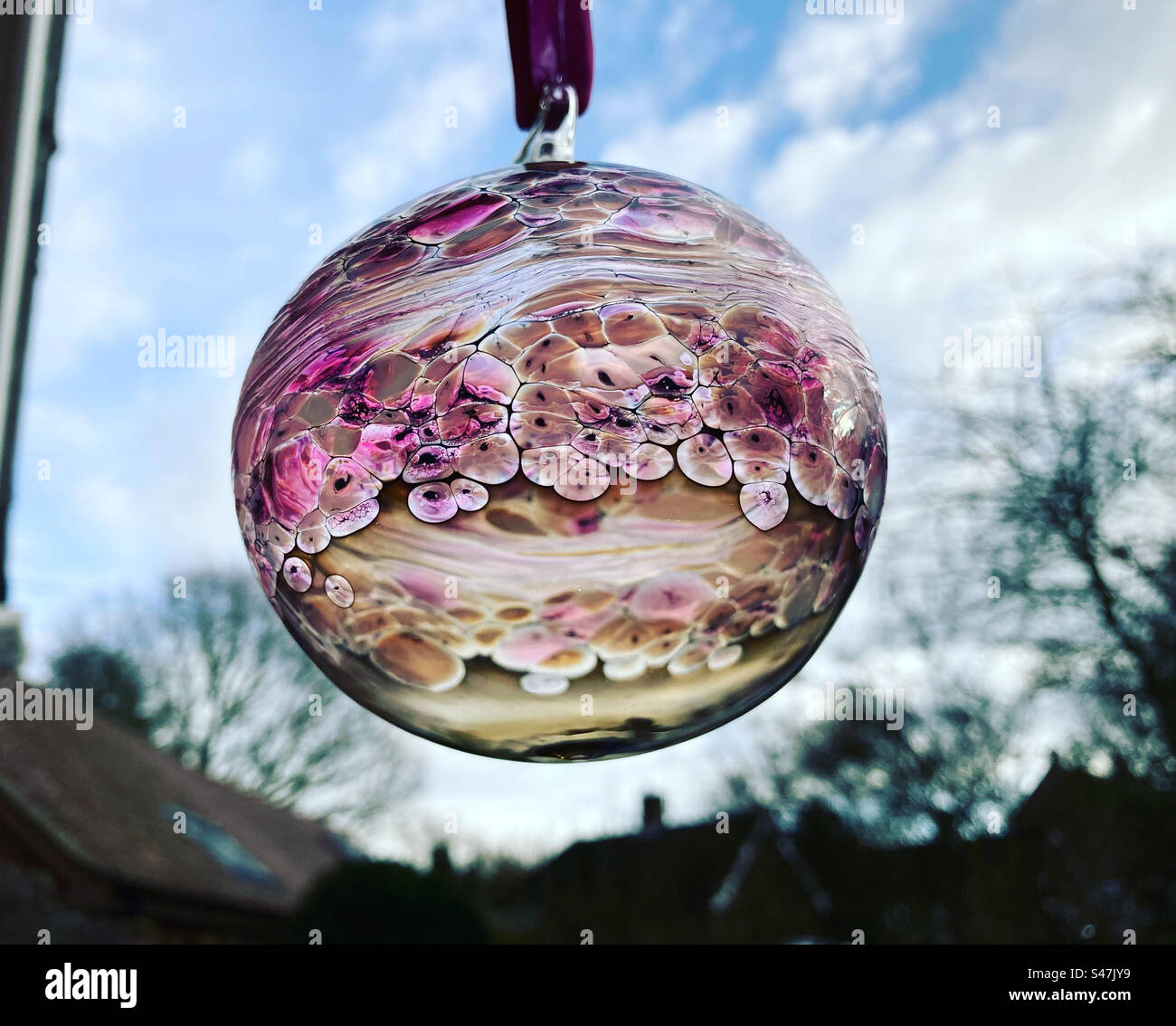 Bauble di Natale traslucido rosa appeso alla finestra Foto Stock