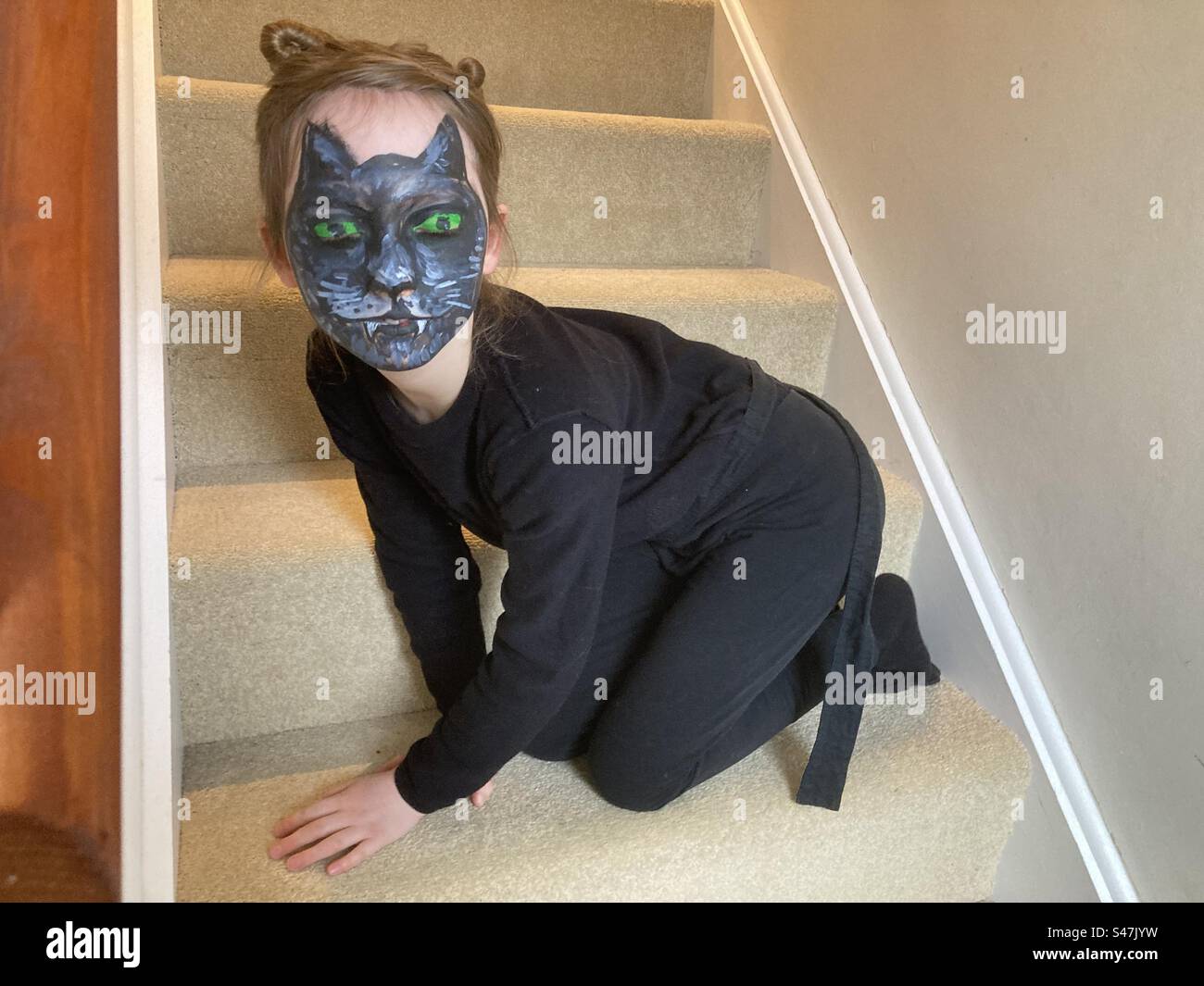 Bambino con una spaventosa vernice leopardata di Halloween vestito da leopardo accovacciato sulle scale Foto Stock