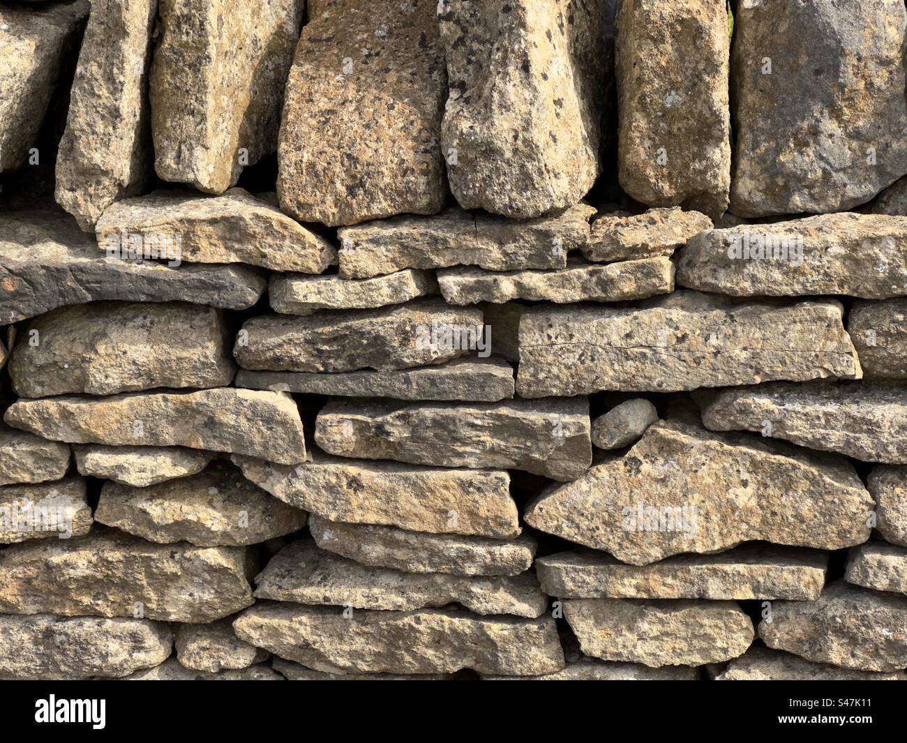 Una sezione di pareti in pietra di legno Cotswold splendidamente lavorate, illuminate dal Sole. - Immagine stock catturata con smartphone
