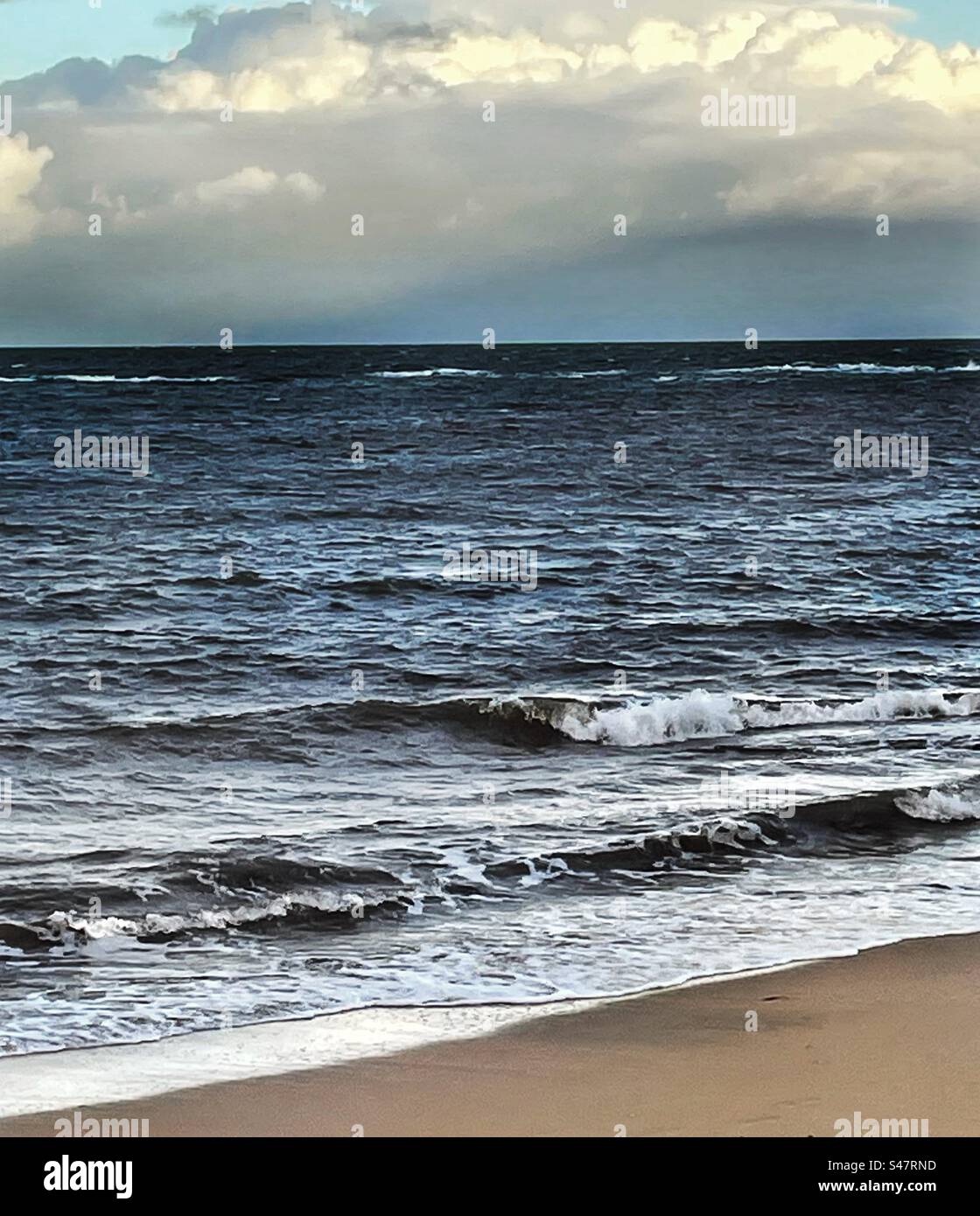 Giornata nuvolosa con acqua scura in spiaggia Foto Stock