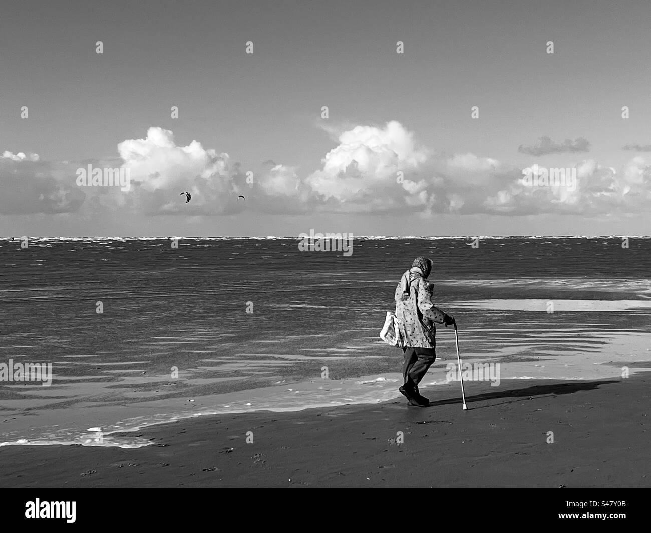 Una vecchia signora cammina sulla spiaggia. Un uomo cammina verso di lei. Quando l'uomo che l'ha appena passata la passa e l'ha salutata. La vecchia sorrideva e iniziava a chiacchierare con l'uomo. Foto Stock