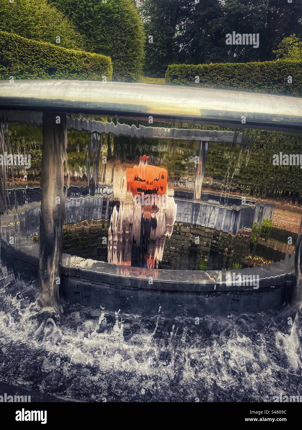 Una faccia sfocata di zucca vista attraverso l'acqua corrente Foto Stock