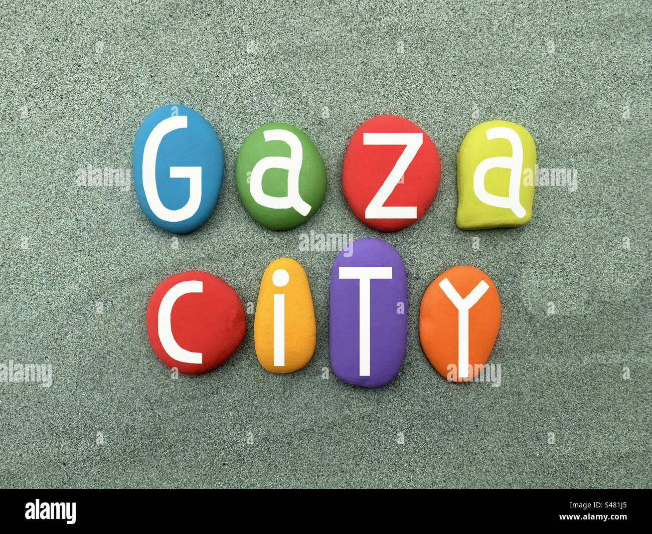 Gaza City, logo creativo composto da lettere di pietra multicolore dipinte a mano su sabbia verde - Immagine stock catturata con smartphone