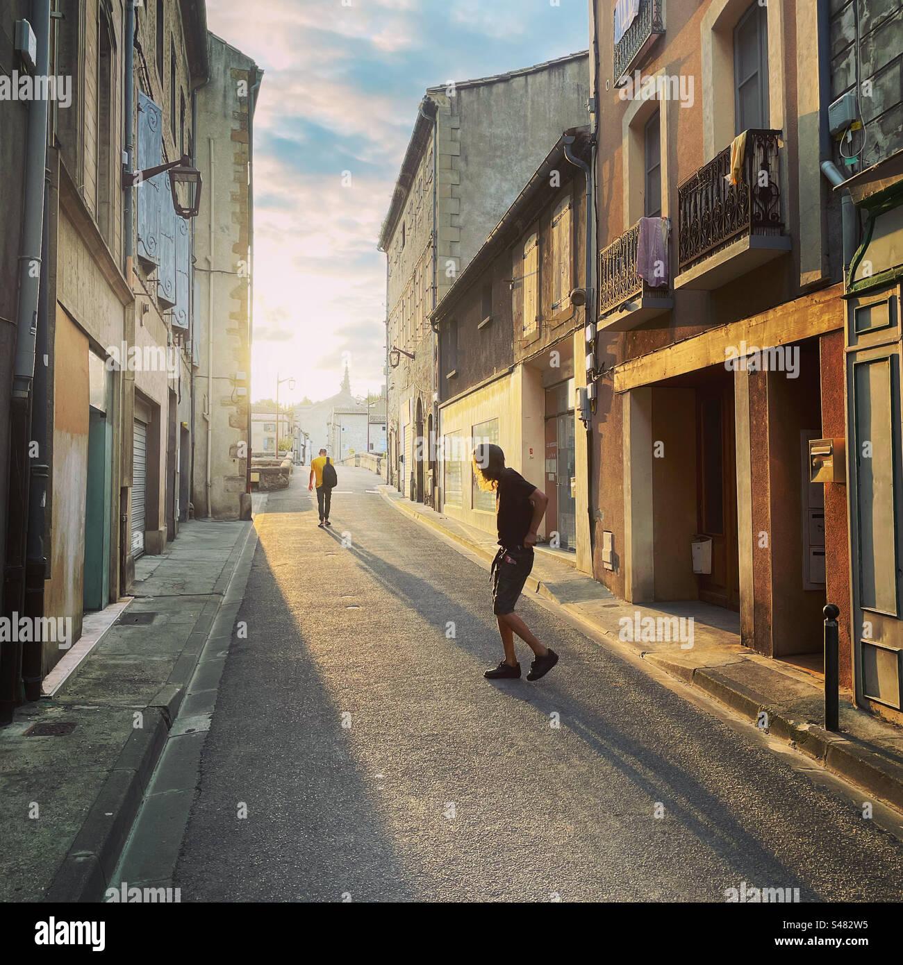 Uomo che lascia la casa nella storica via di Limoux con una luce soffusa del mattino presto in colori pastello e ombre. Foto Stock
