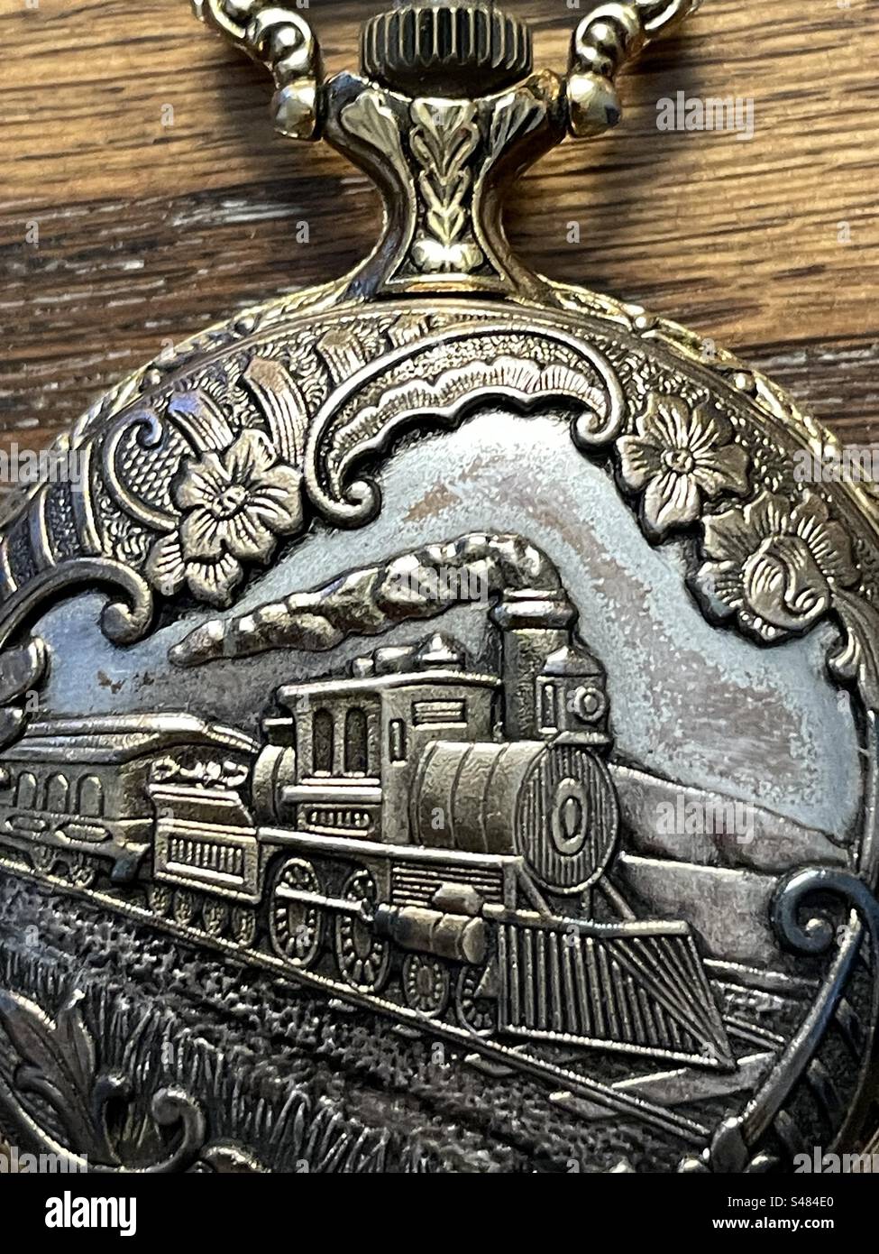Un orologio da tasca con una locomotiva in rilievo sul davanti. - Immagine stock catturata con smartphone