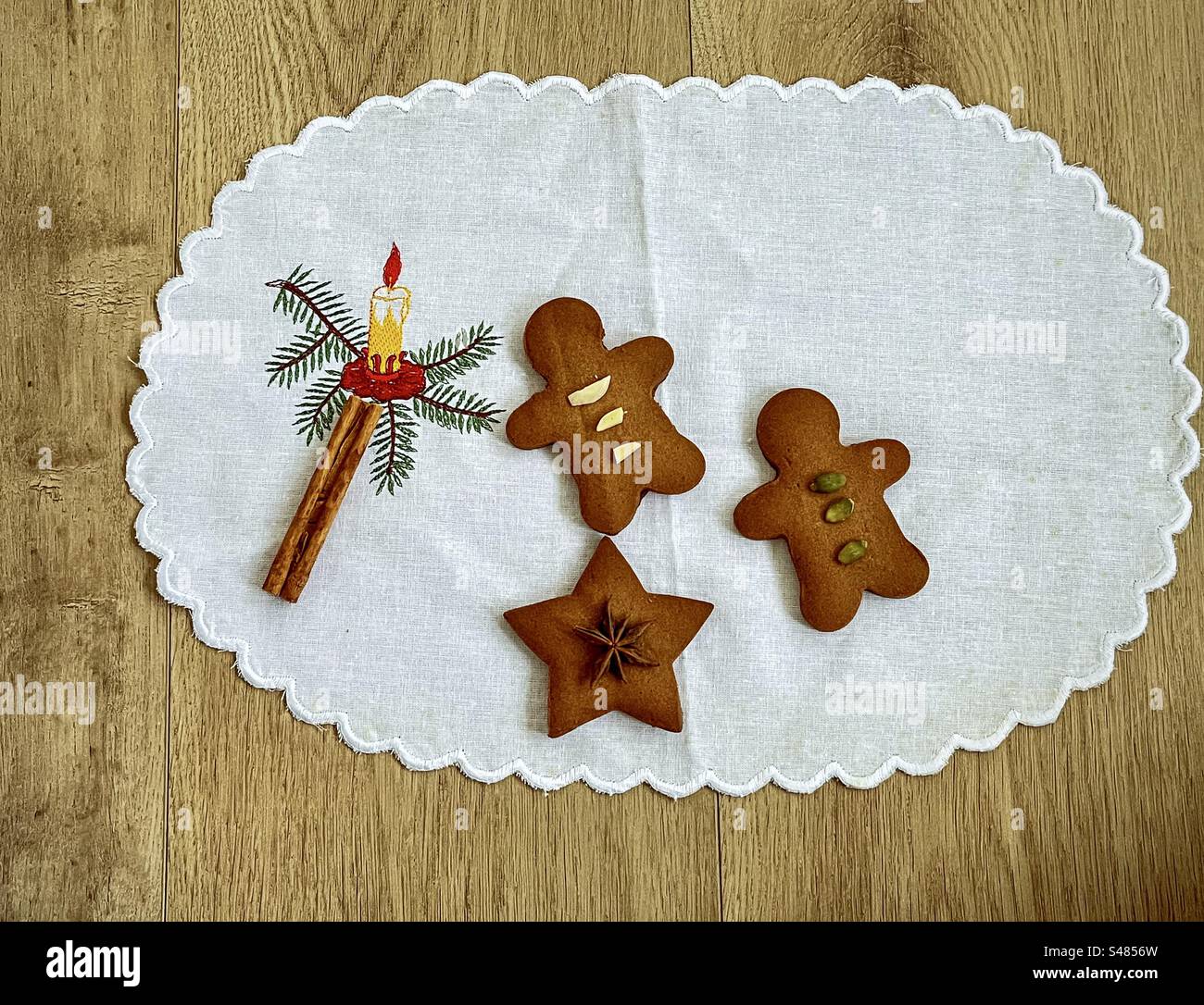 Stile vintage natalizio. Copia spazio. Piatto di due zenzero e un biscotto stellato con noci e spezie su tovaglia bianca ricamato con candela di Natale su un tavolo di legno. Natura morta. - Immagine stock catturata con smartphone