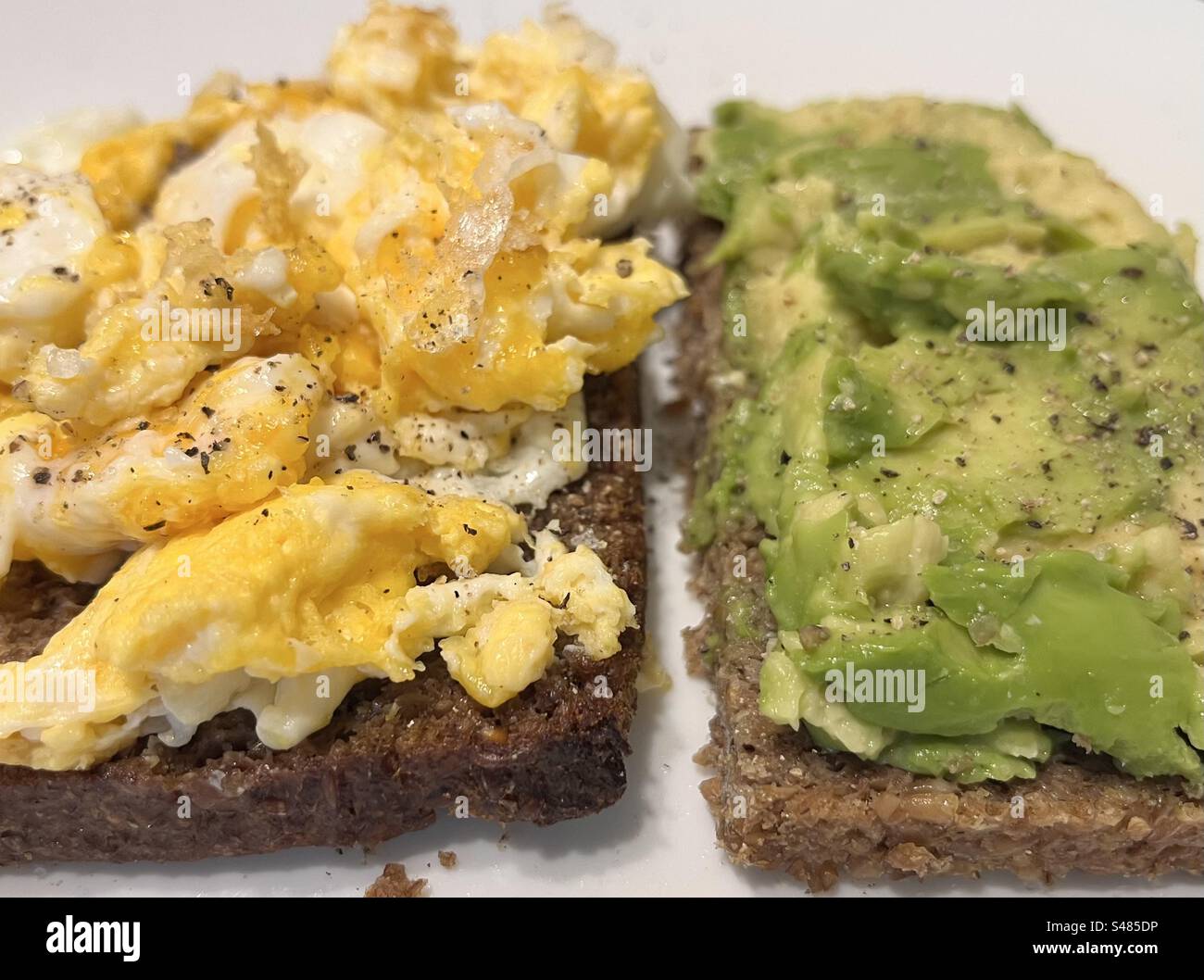 Uova strapazzate e avocado schiacciato su pane tostato, sana e nutriente colazione Foto Stock