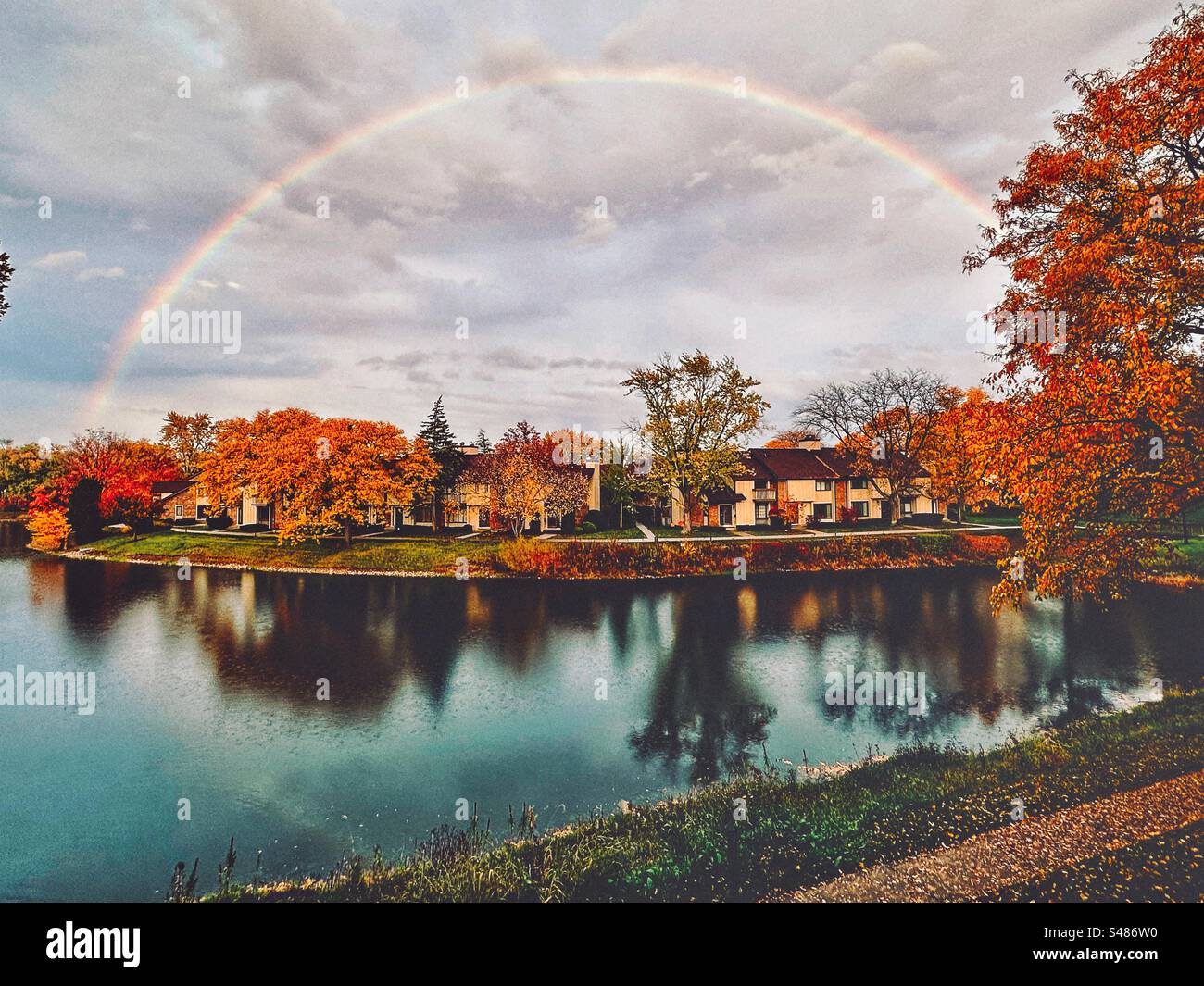 Splendidi colori autunnali con un arcobaleno sopra un lago Foto Stock