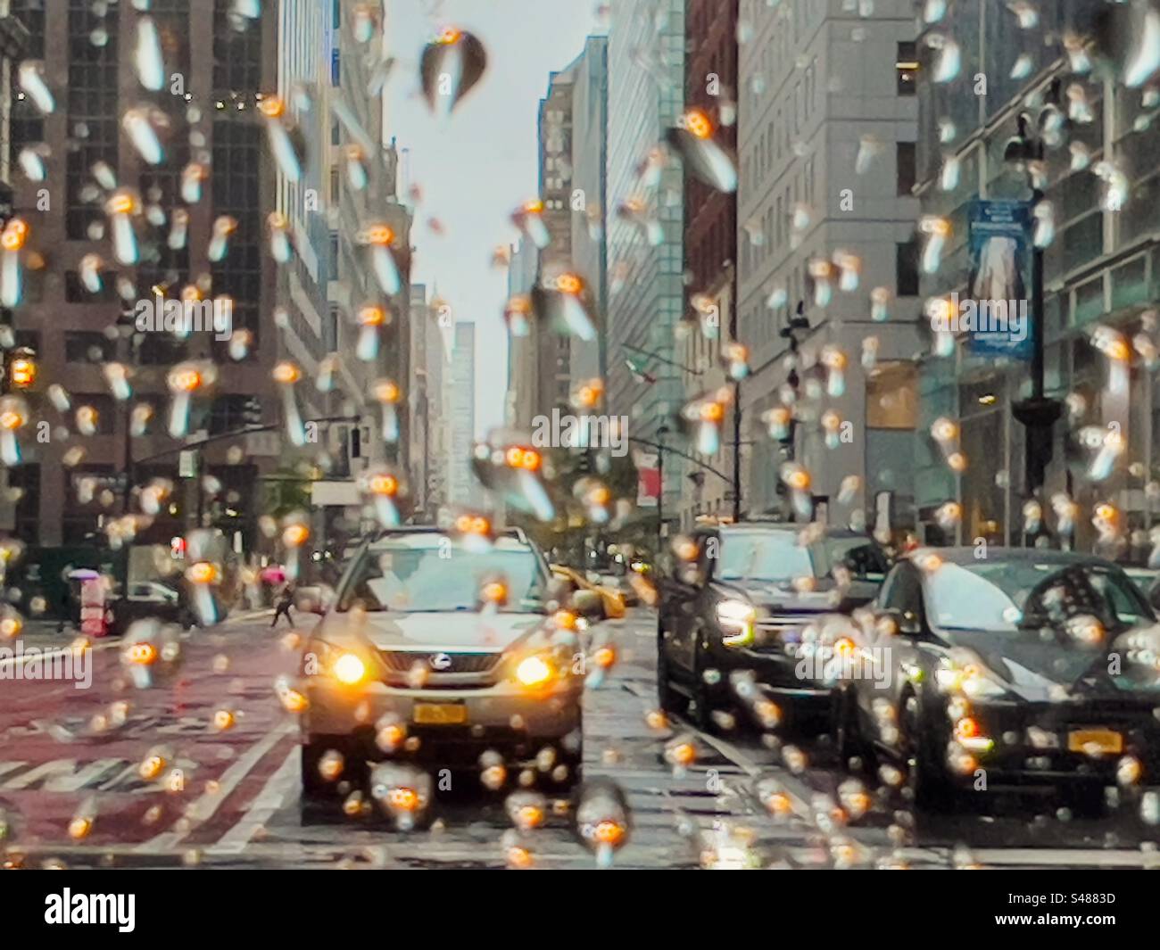 Giornata di pioggia a New York con i fari dell'auto riflessi dalle gocce di pioggia sul finestrino dell'auto Foto Stock