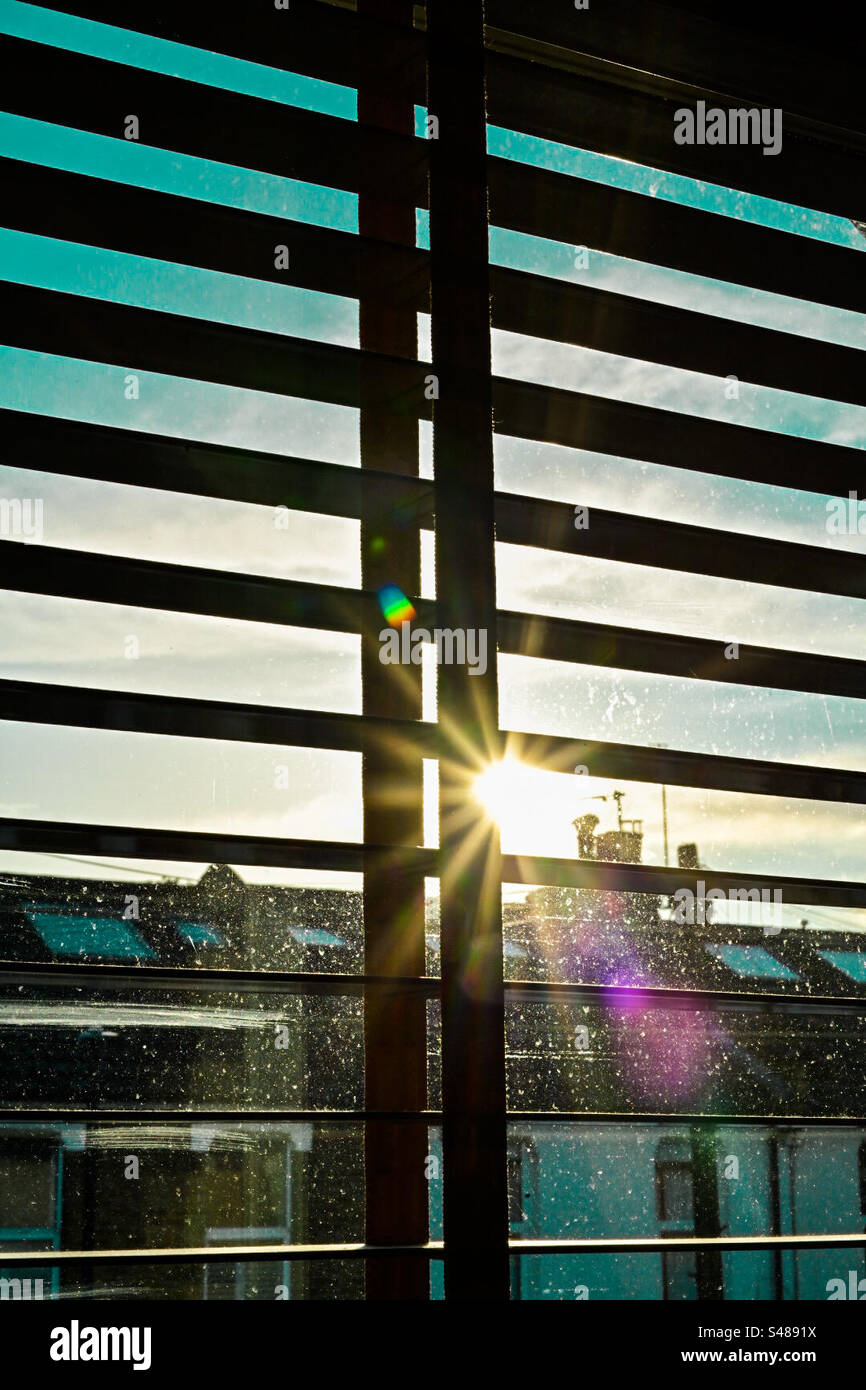 Il sole splende attraverso le tende della finestra la sera Foto Stock