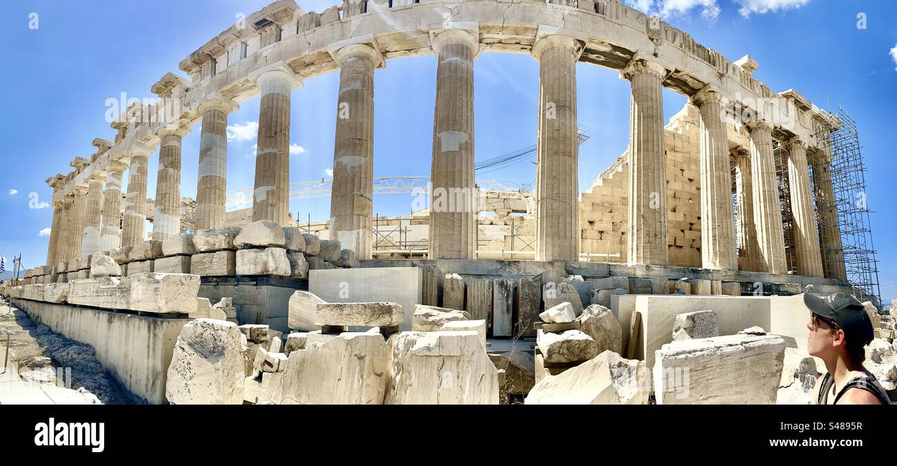 Panorama del Partenone con un giovane che guarda e ammira l'incredibile struttura dell'Acropoli di Atene. - Immagine stock catturata con smartphone
