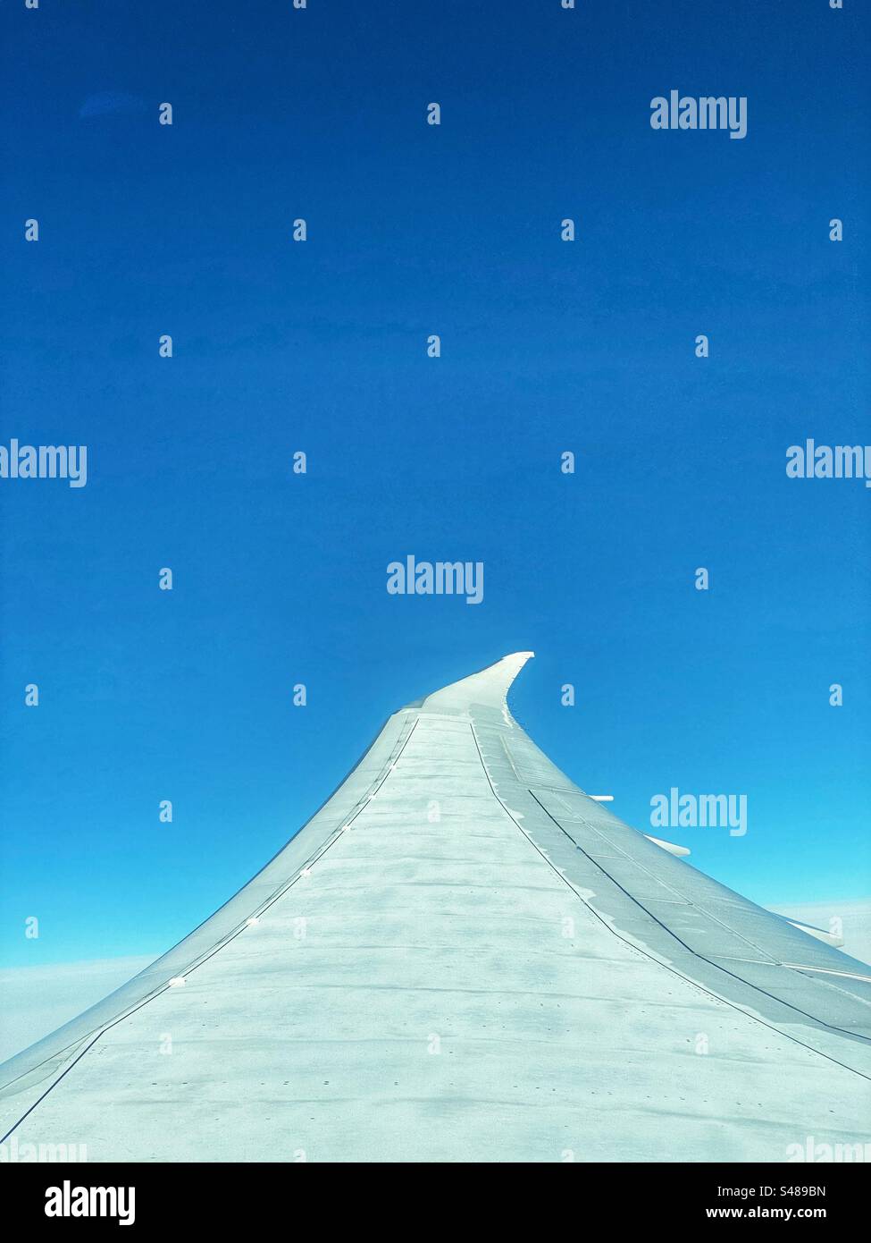 Ala di un aereo contro un cielo blu brillante Foto Stock